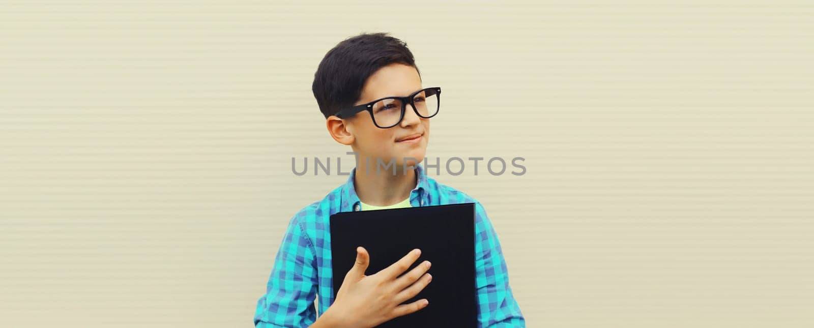 Portrait of happy teenager boy in eyeglasses with folder or book looking away on white background, back to school