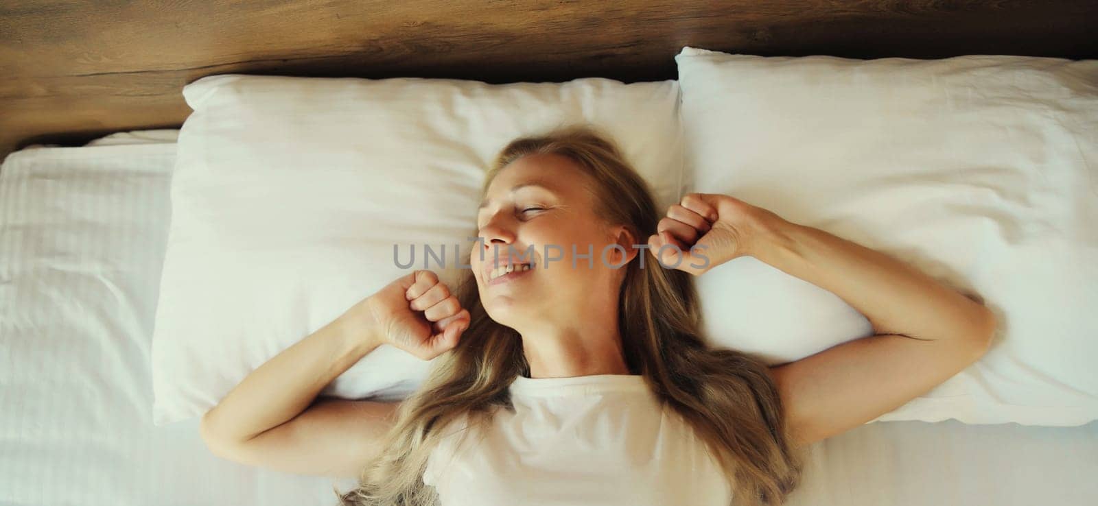 Happy young woman sleeping lying in bed on white soft comfortable pillow in bedroom at home