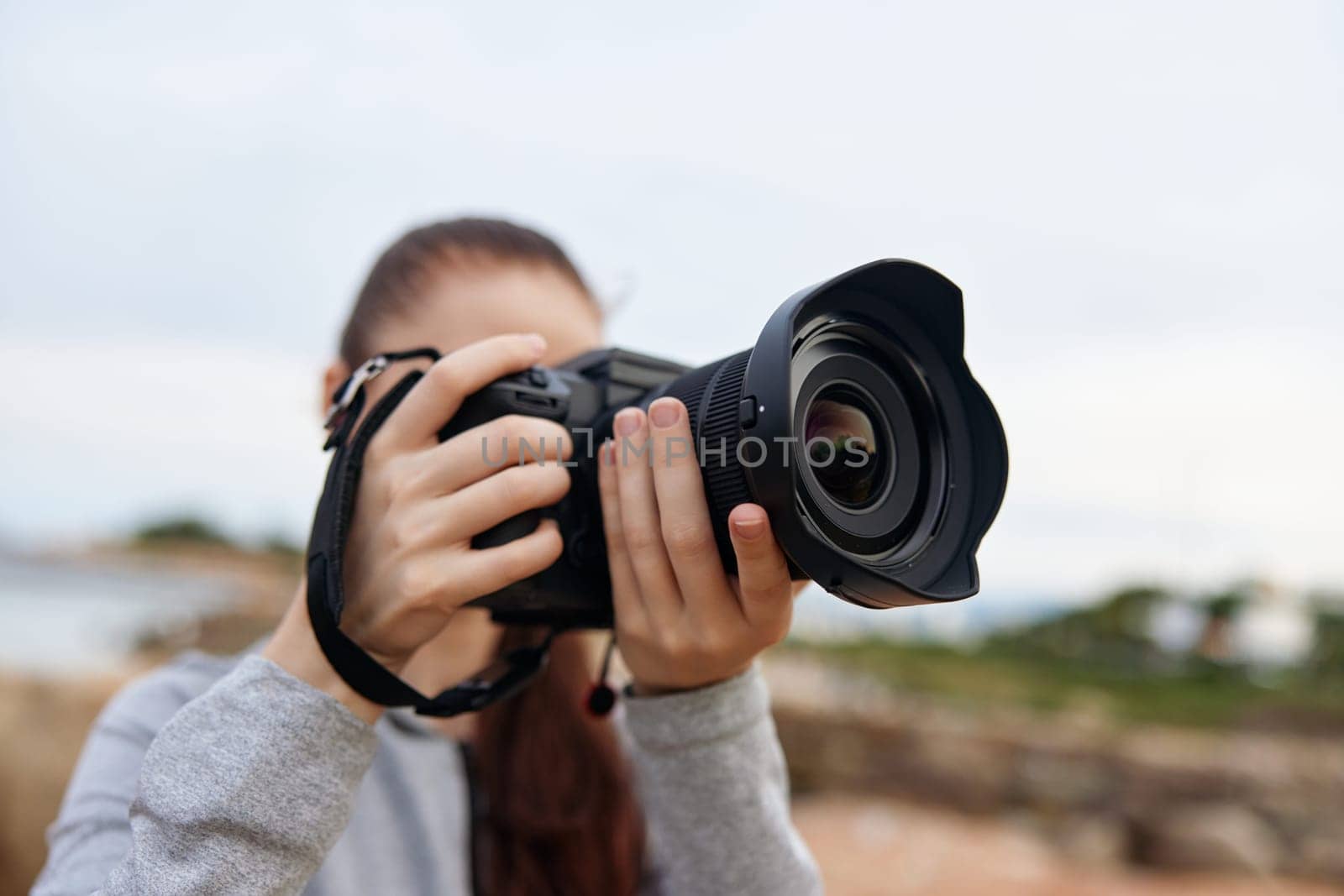 A young woman with a camera displays her passion for photography, showcasing emotions of creativity and enthusiasm in a vibrant outdoor landscape, perfect for nature and outdoor themes