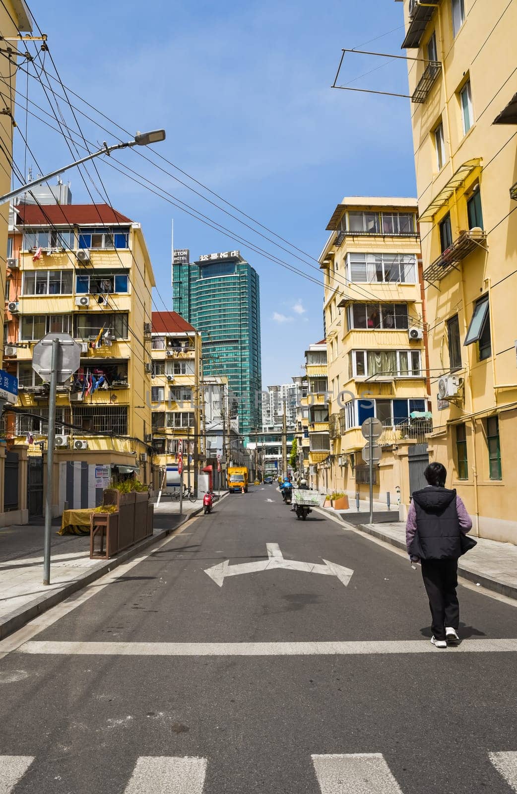 Shanghai, China - 1 April 2025: View of a quiet street in Pudong district, with yellow residential buildings and the Eaton Hotel in the background