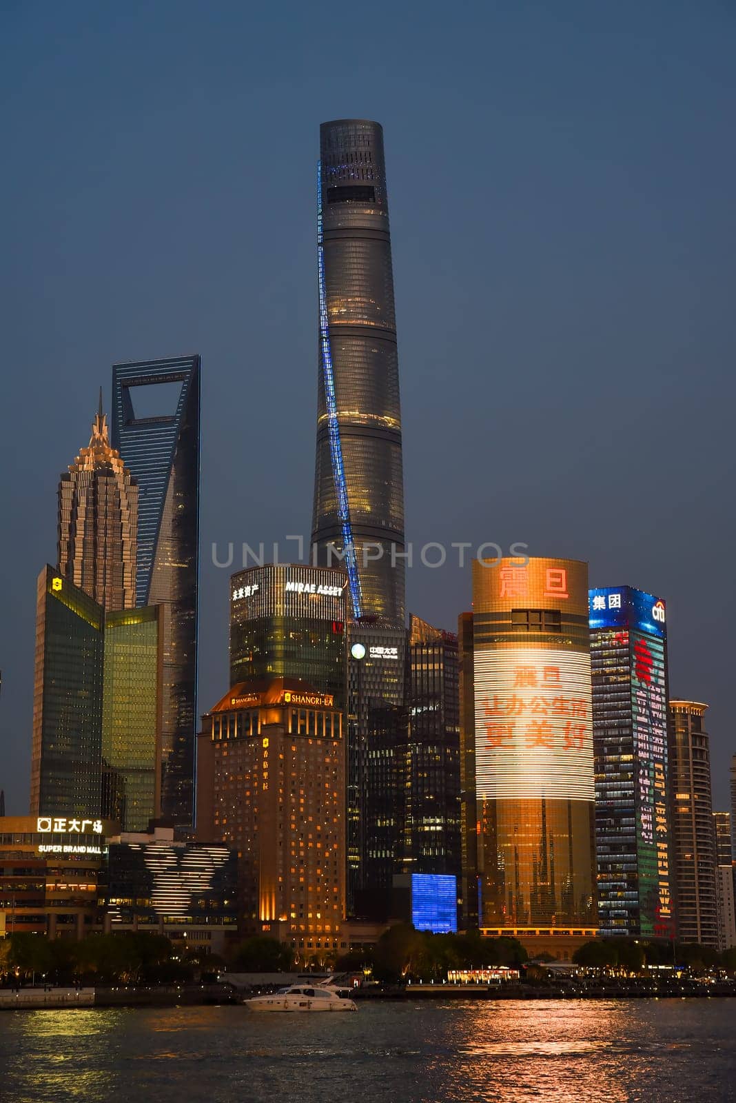 Shanghai, China - 1 April 2025: Evening skyline of Pudong district featuring illuminated Shanghai Tower, Shanghai World Financial Center, and Jin Mao Tower reflected in Huangpu River