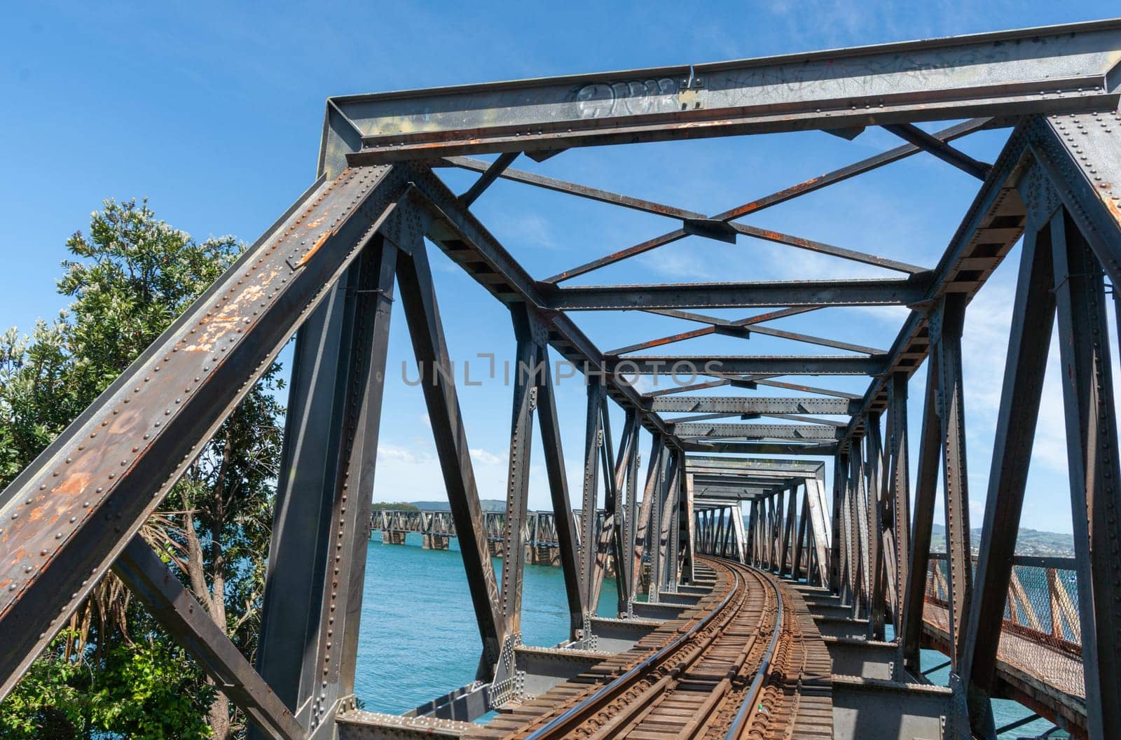 Tauranga historic railway bridge crossing harbour with leading lines of railway tracks.