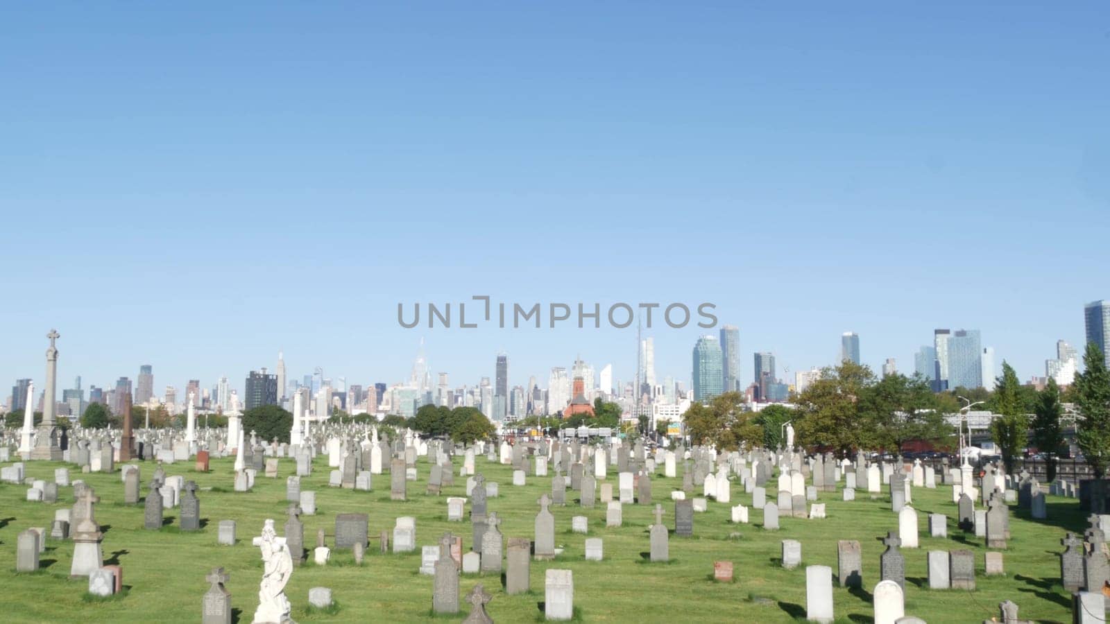 New York City, United States - 14 Sept 2023: Calvary cemetery in Queens, USA. Manhattan Midtown urban skyline cityscape architecture. Tombstones on graves, huge graveyard. Large cemetry grass lawn.