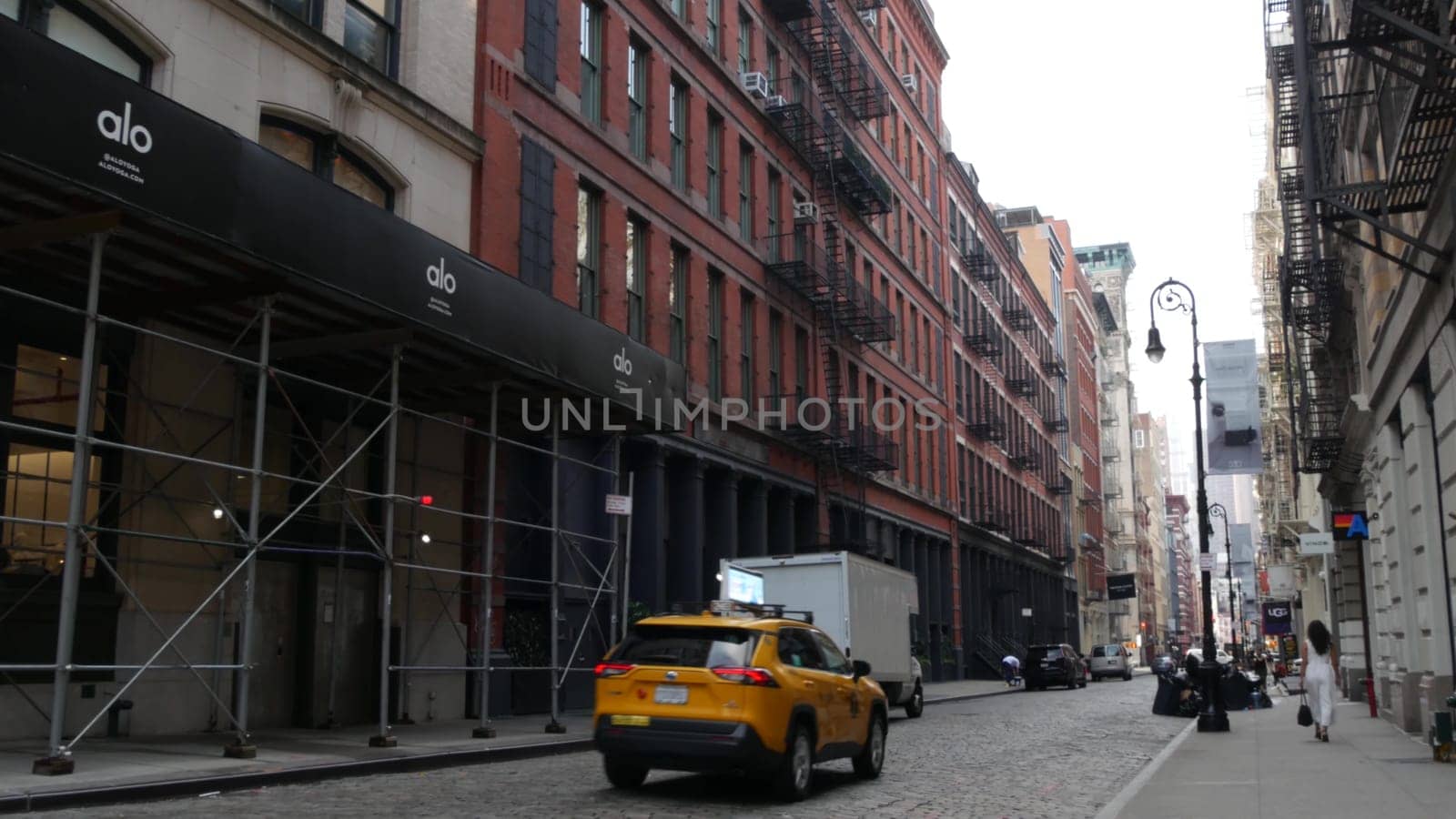 New York City, United States - 8 Sept 2023: Manhattan Soho fashion district near Broadway street. USA urban building facade, old classic american architecture. Shopping in NYC. People, yellow taxi cab