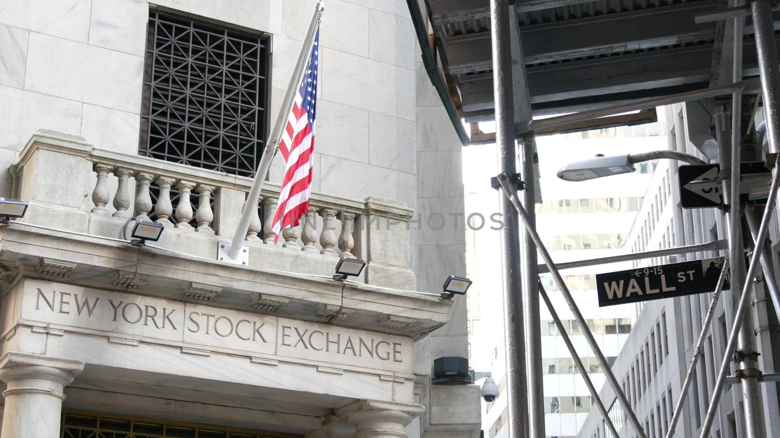 New York City, United States - 4 Sept 2023: Lower Manhattan Downtown Financial District architecture. Wall street road sign near Stock Exchange building, USA Stock Market. Scaffolding, American Flag.
