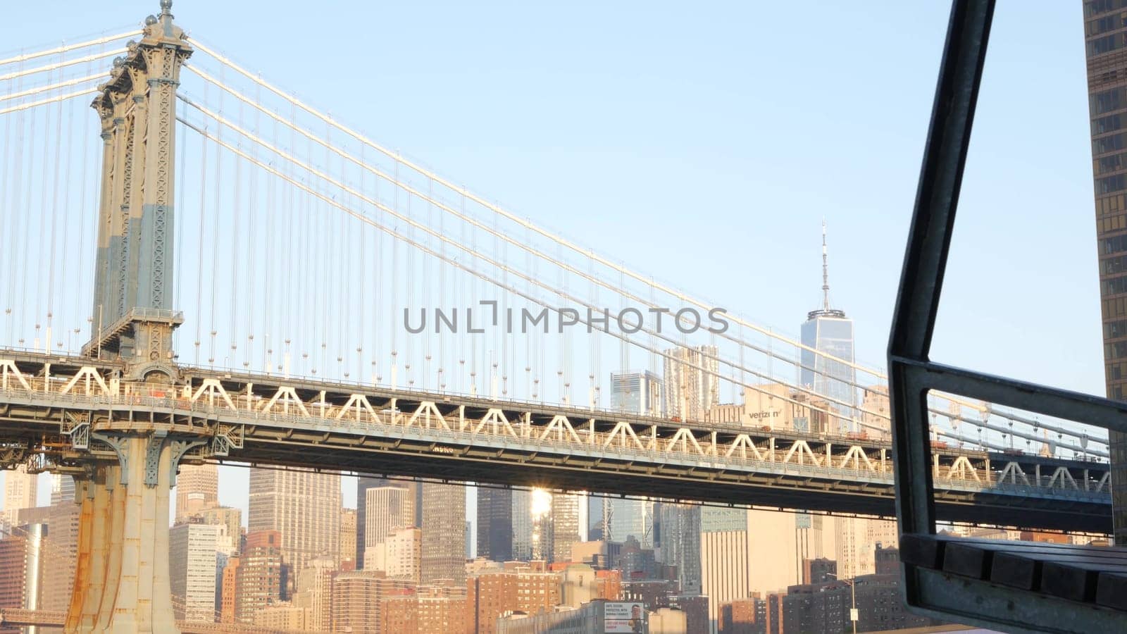 New York City, United States - 7 Sept 2023: Manhattan Bridge to Brooklyn. Pier 35 swings bench, waterfront downtown skyline cityscape. World Trade Center skyscraper, financial district morning sunset.