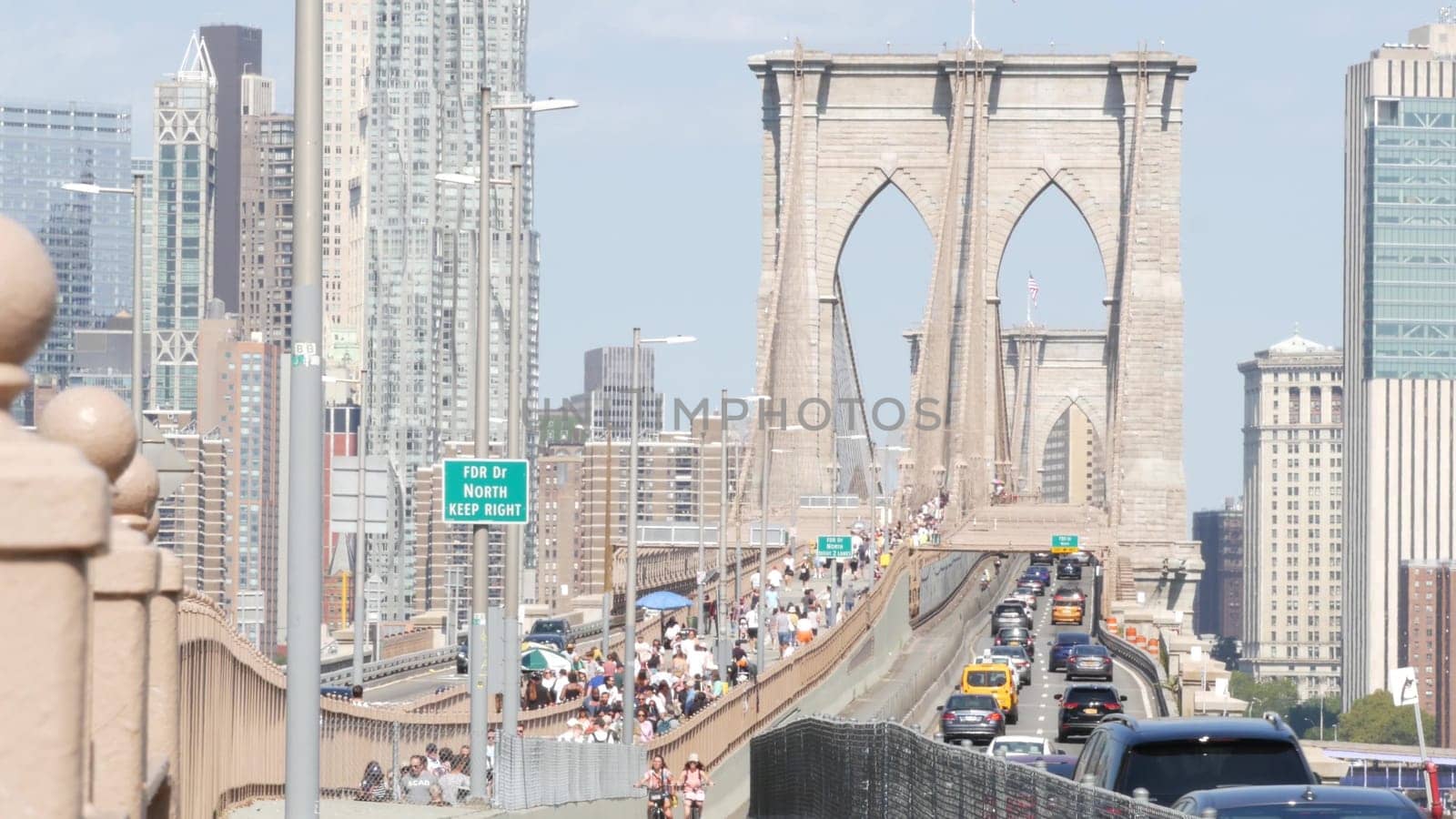 New York City, United States - 3 Sept 2023: Cars on Brooklyn Bridge from Manhattan downtown to Dumbo. Financial district skyline cityscape. Road traffic, people walking and USA architecture.
