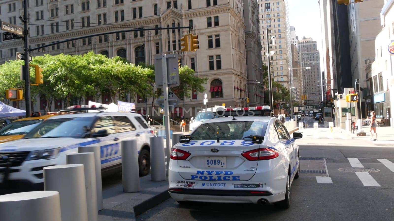 New York City, United States - 31 Aug 2023: Police patrol car, USA NYPD, 911 vehicle on Manhattan Downtown street. American cop auto siren light. Urban traffic, road transport scene. Yellow taxi cab.