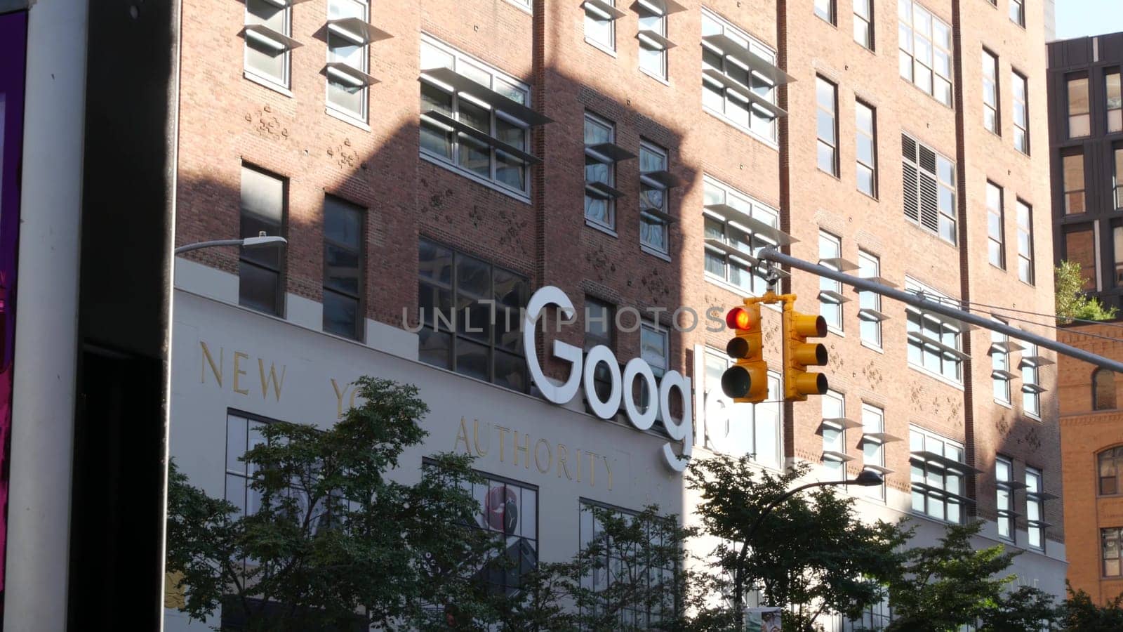 New York City, United States - 1 Sept 2023: Manhattan Midtown street or avenue. Urban red brick architecture USA. Google logo. Headquarters office near Chelsea Market, High Line. Yellow traffic light.