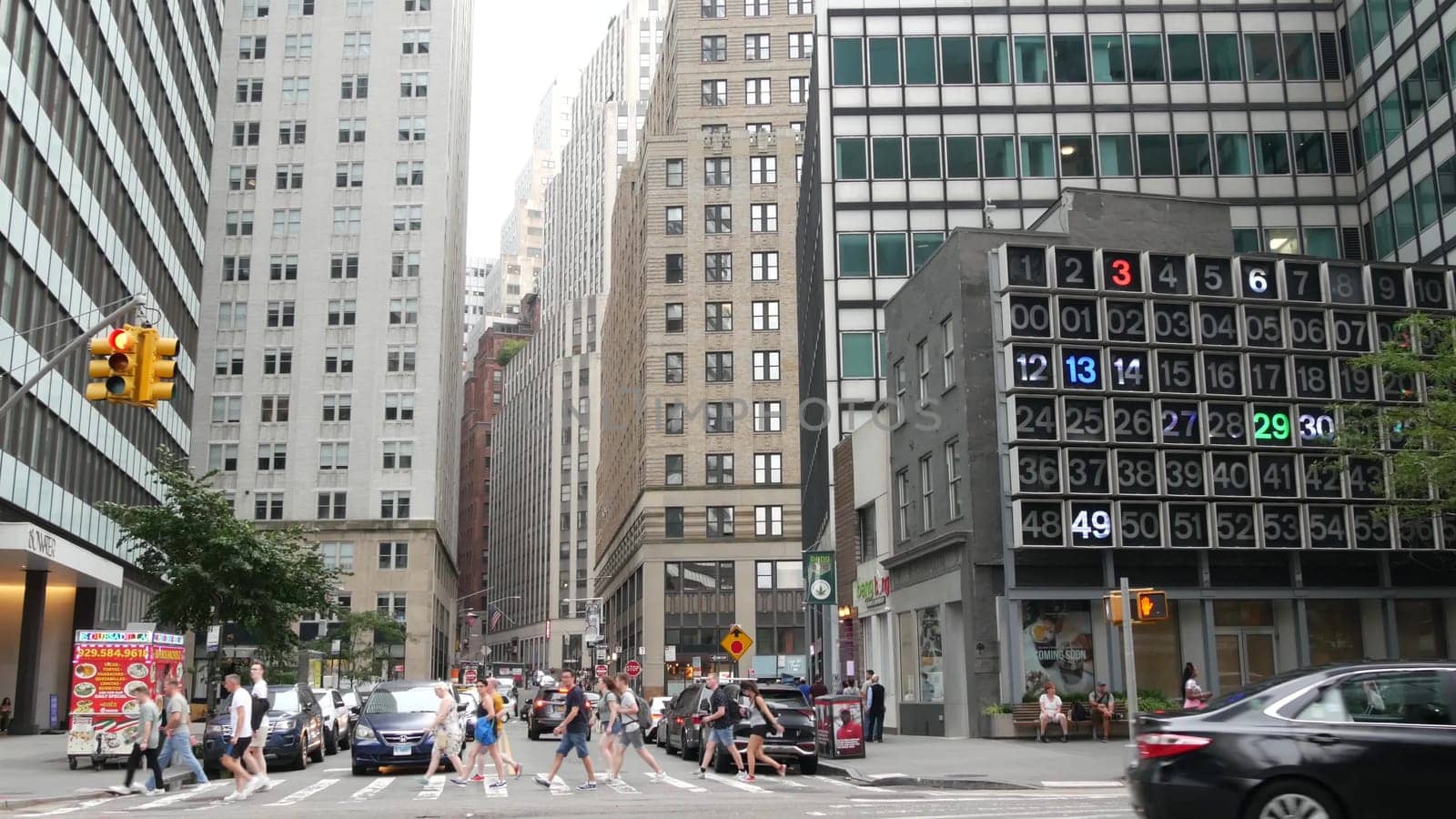 New York City, United States - 9 Sept 2023: Manhattan Downtown Financial District Water and John street crossroad intersection. USA road car traffic. Yellow taxi, people. Digital clock, bingo board.