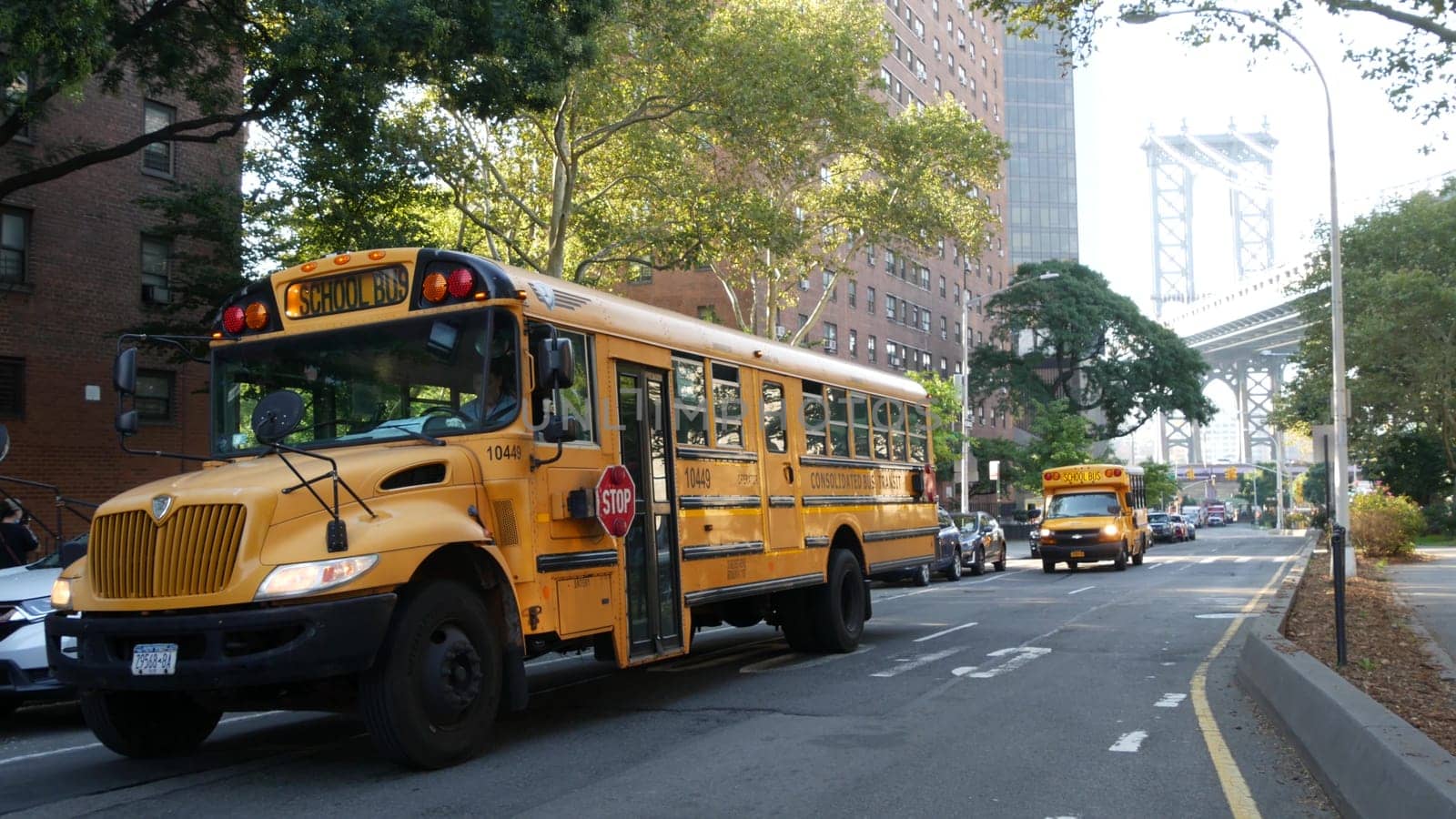 New York City, United States - 7 Sept 2023: Yellow School Bus, Manhattan bridge, schoolbus truck, city street. Children education and USA transportation. American residential district school shuttle.