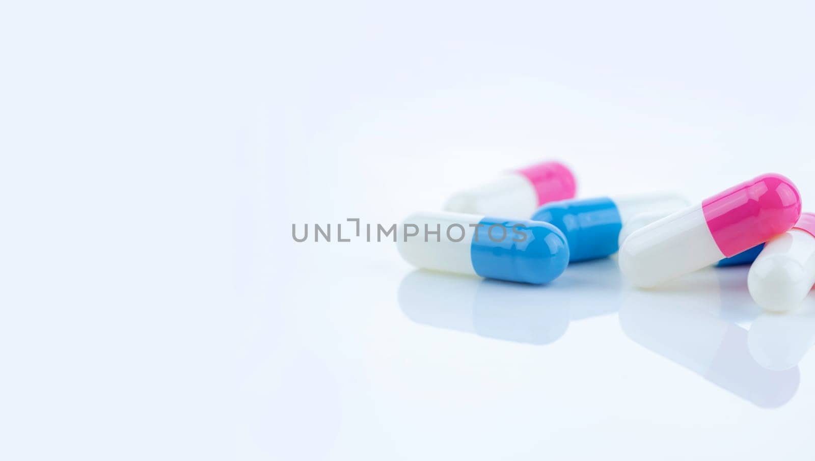 Blue and pink capsule pills spread on white background, showcasing pharmaceutical products, healthcare concepts, and the role of prescription medicine in advancing treatment and patient well-being.