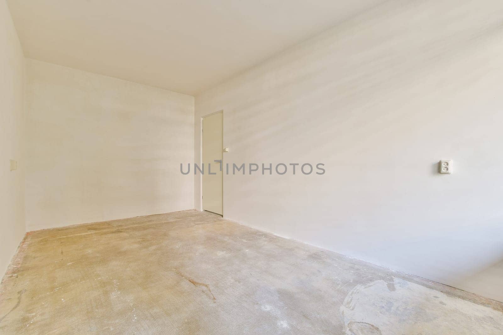 An empty, minimalist interior space featuring a bare wall and natural lighting, creating an open and airy atmosphere suitable for various uses.