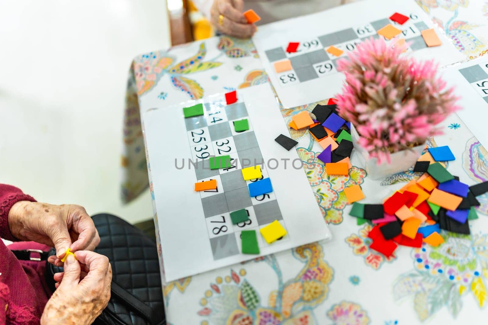 Elderly woman concentrating on bingo game, demonstrating cognitive engagement and social interaction in a nursing home environment