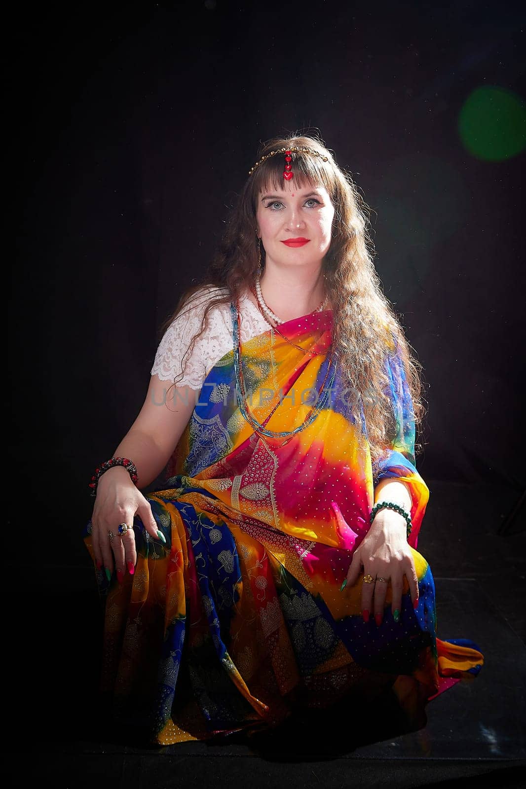 A mature blonde woman showcases elegance while posing in a vibrant sari for an Indian themed photoshoot, highlighting cultural beauty and fashion.