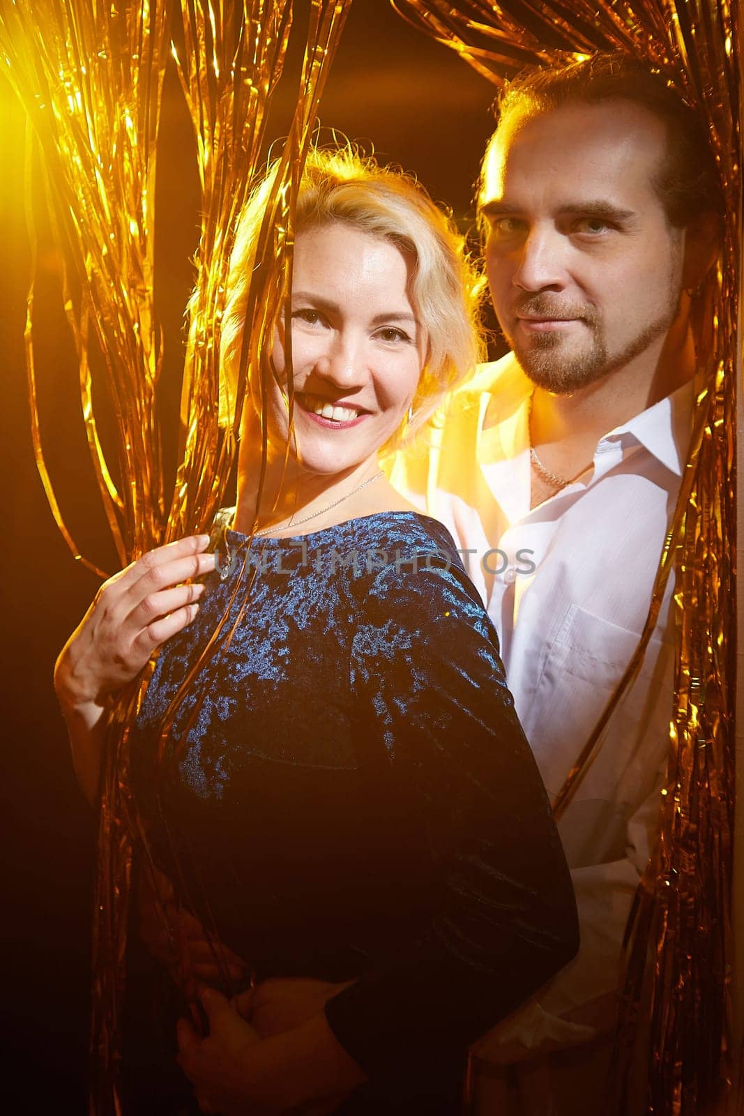A happy couple poses together amidst cheerful decorations, celebrating the warmth of the Christmas and New Year holidays.