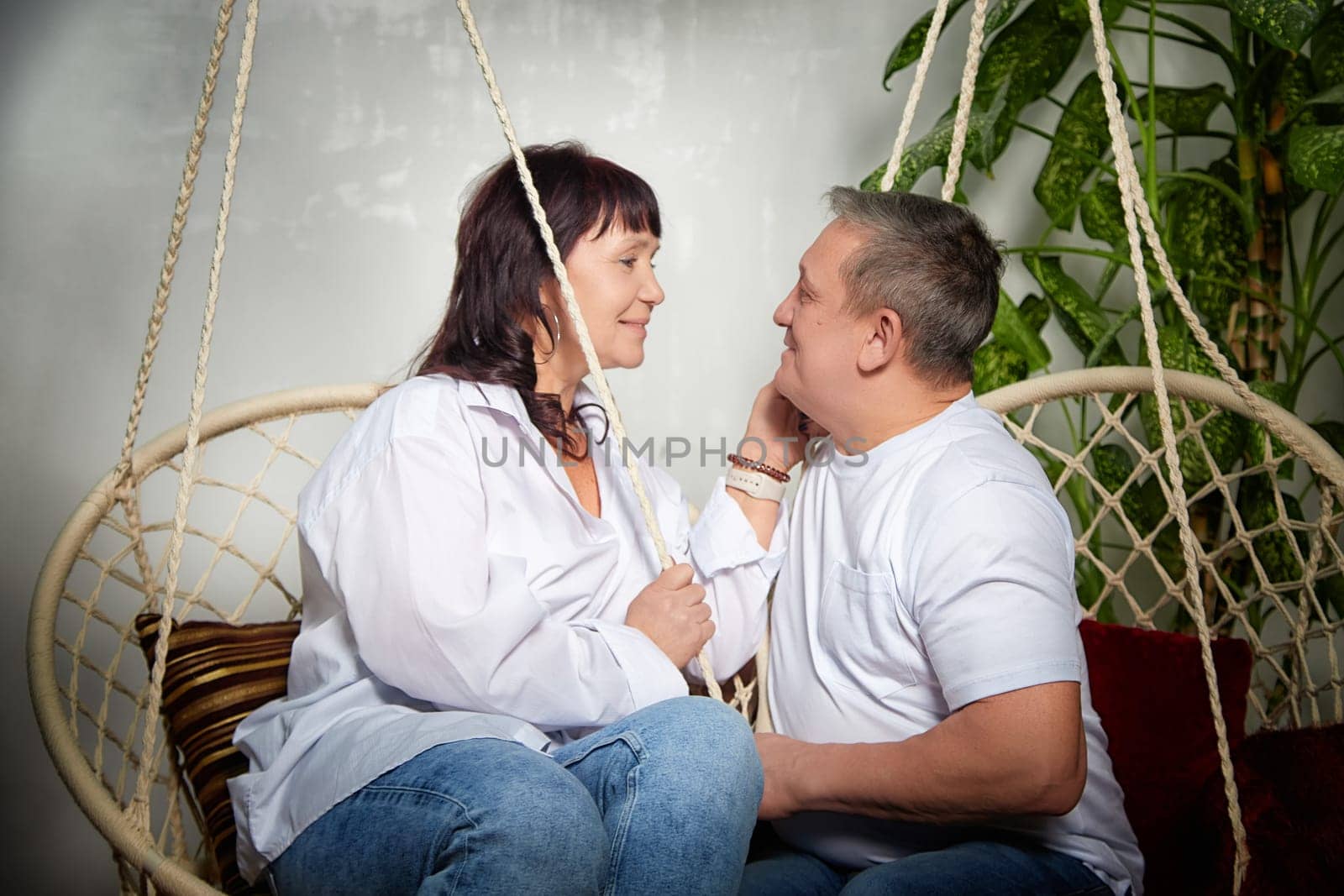 A middle-aged couple shares a tender moment indoors, embracing in a cozy atmosphere filled with love and happiness during their photoshoot.