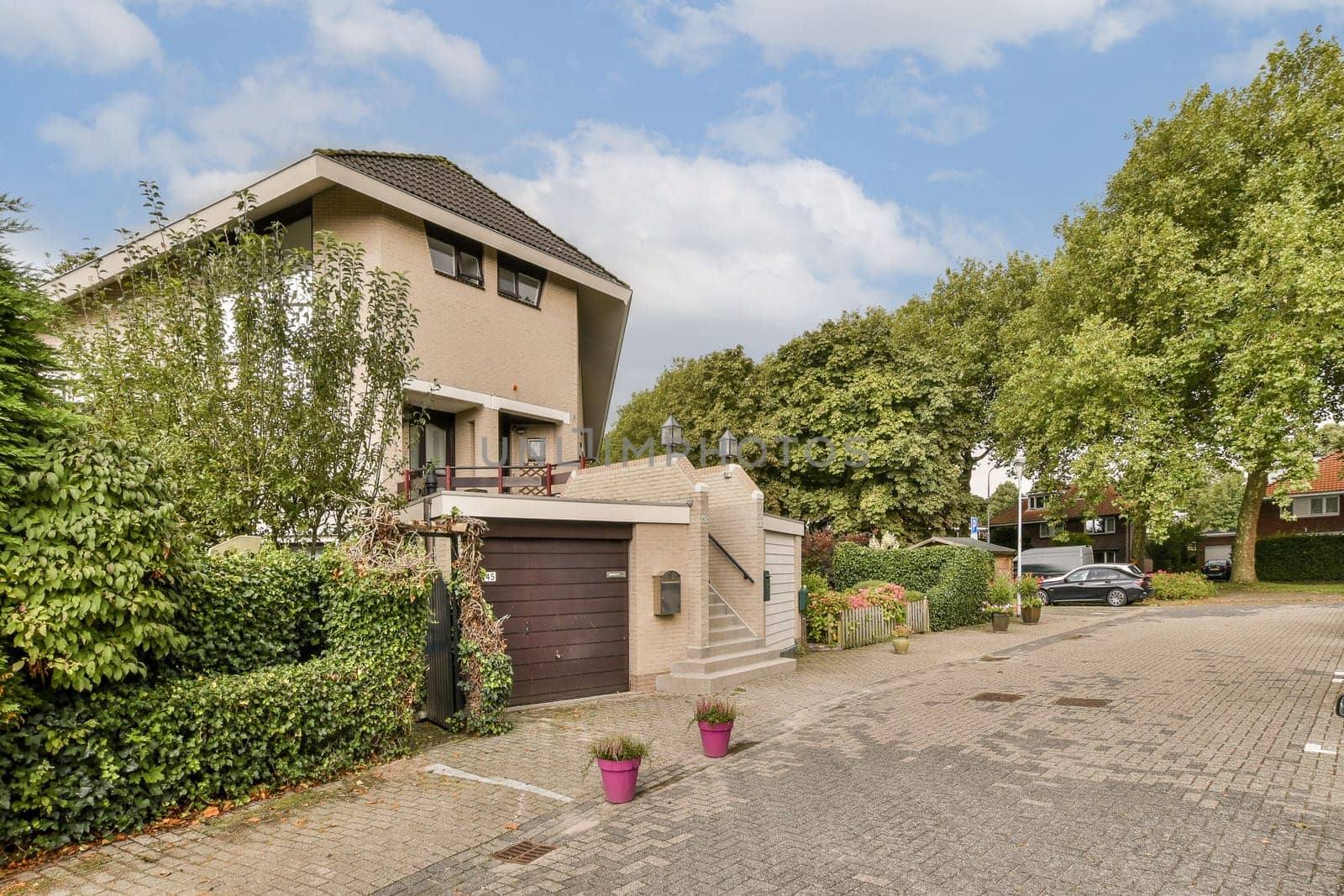 A contemporary home featuring a well-maintained garden and driveway, situated in a serene suburban neighborhood with lush greenery.
