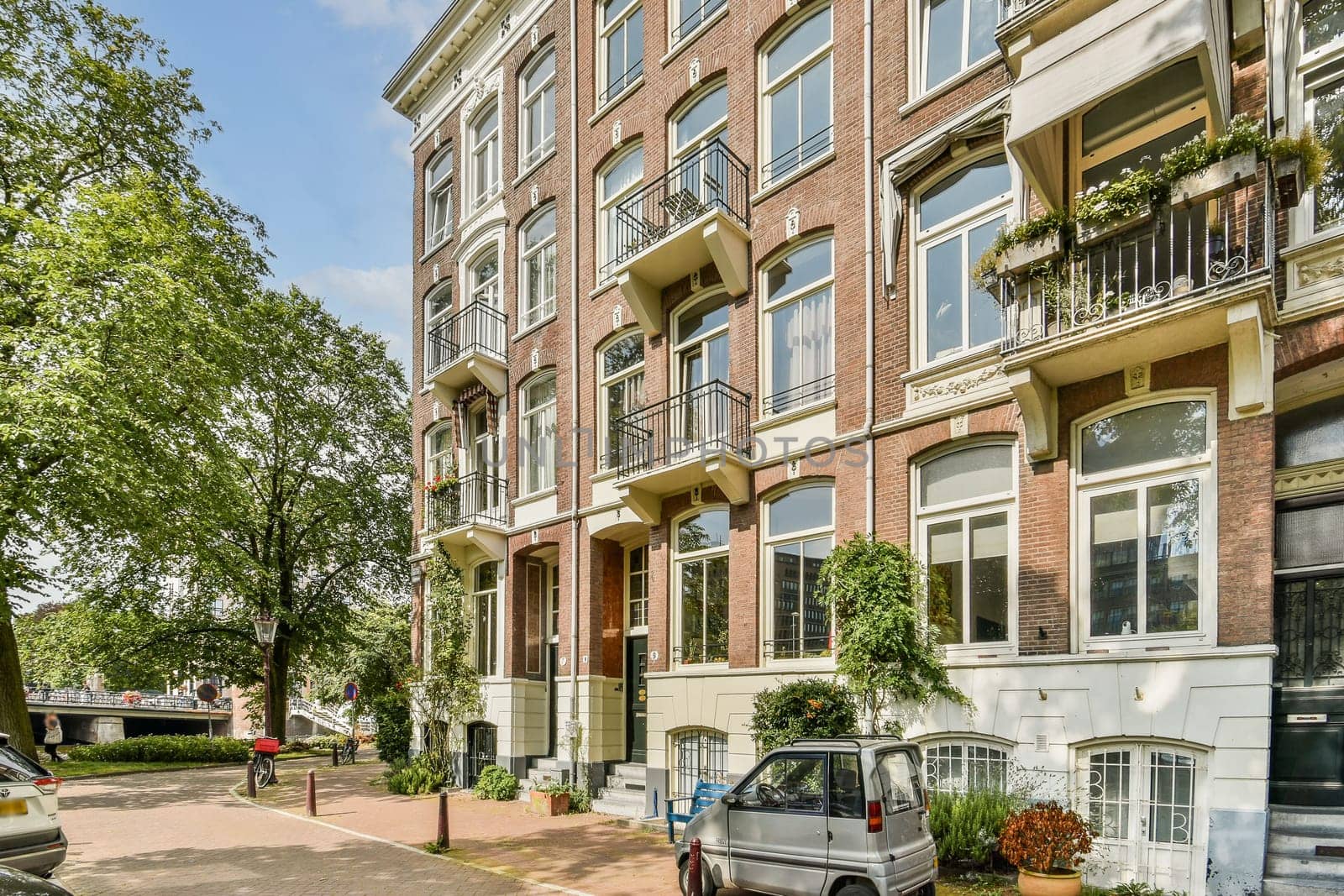 A picturesque scene showcasing classic European architecture, featuring detailed brickwork, balconies, and lush greenery lining a tranquil street.