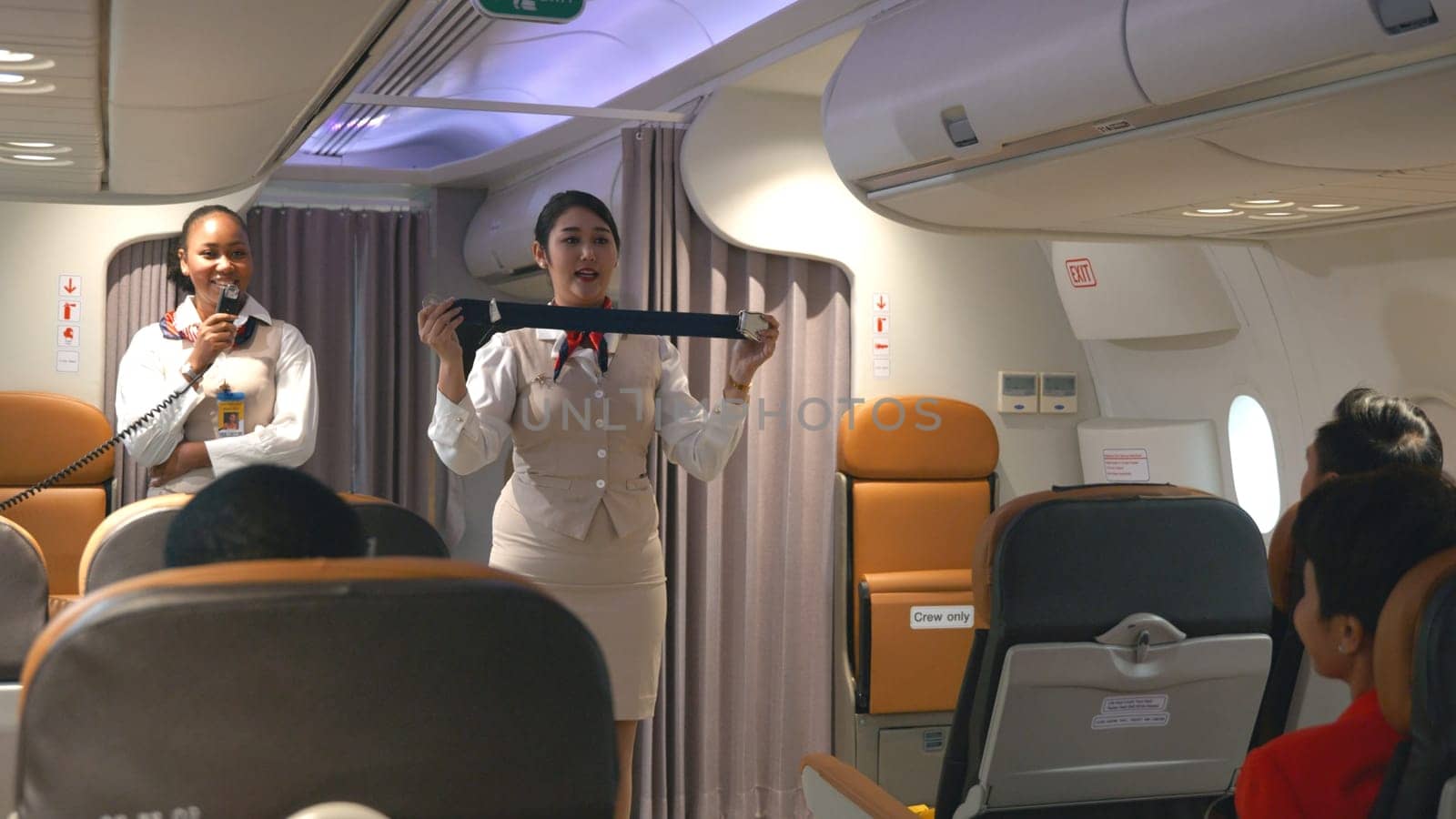 Asian stewardess safety explaining passengers how to use seat belt fastening in airplane, air hostess uniform safety demonstration presenting a seat belt, aircraft safety