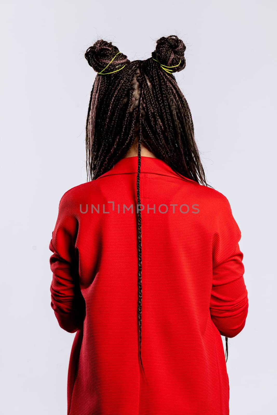 A stylish woman with braided hair and a vibrant red jacket poses confidently, showcasing a modern and trendy look