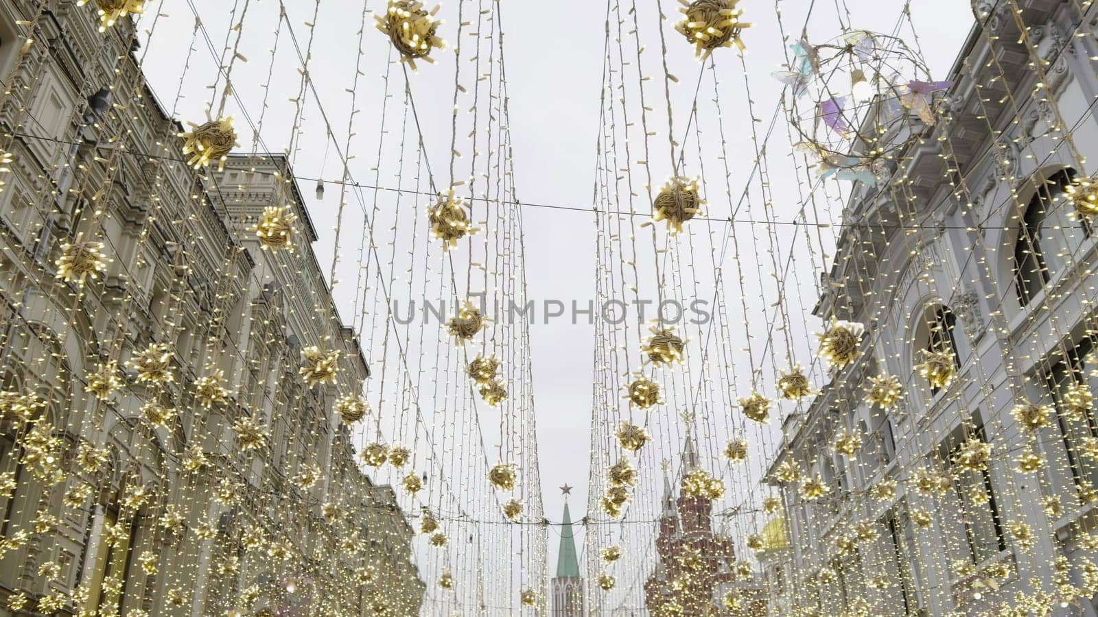 Festive atmosphere in moscow with golden decorations illuminating nikolskaya street, featuring the kremlin tower in the distance