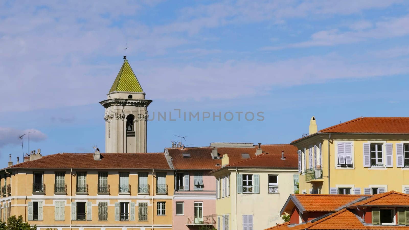 Traditional colorful buildings with a church tower under blue sky in nice, france