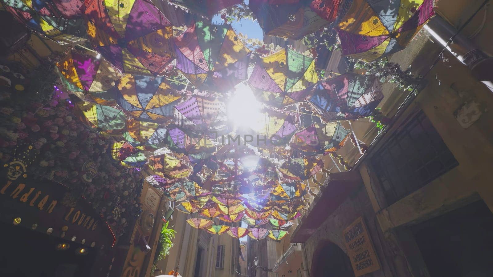 Umbrellas and decorations suspended above a pedestrian street create a vibrant and celebratory ambiance