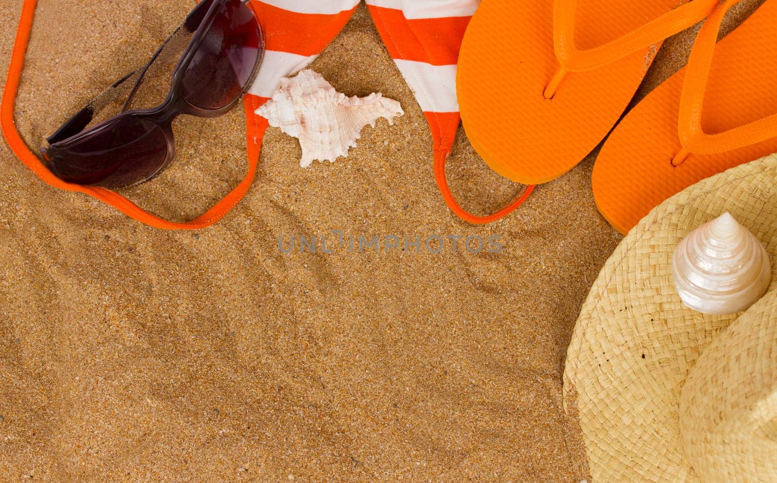 orange sandals  and sunbathing accessories at sand with copy space