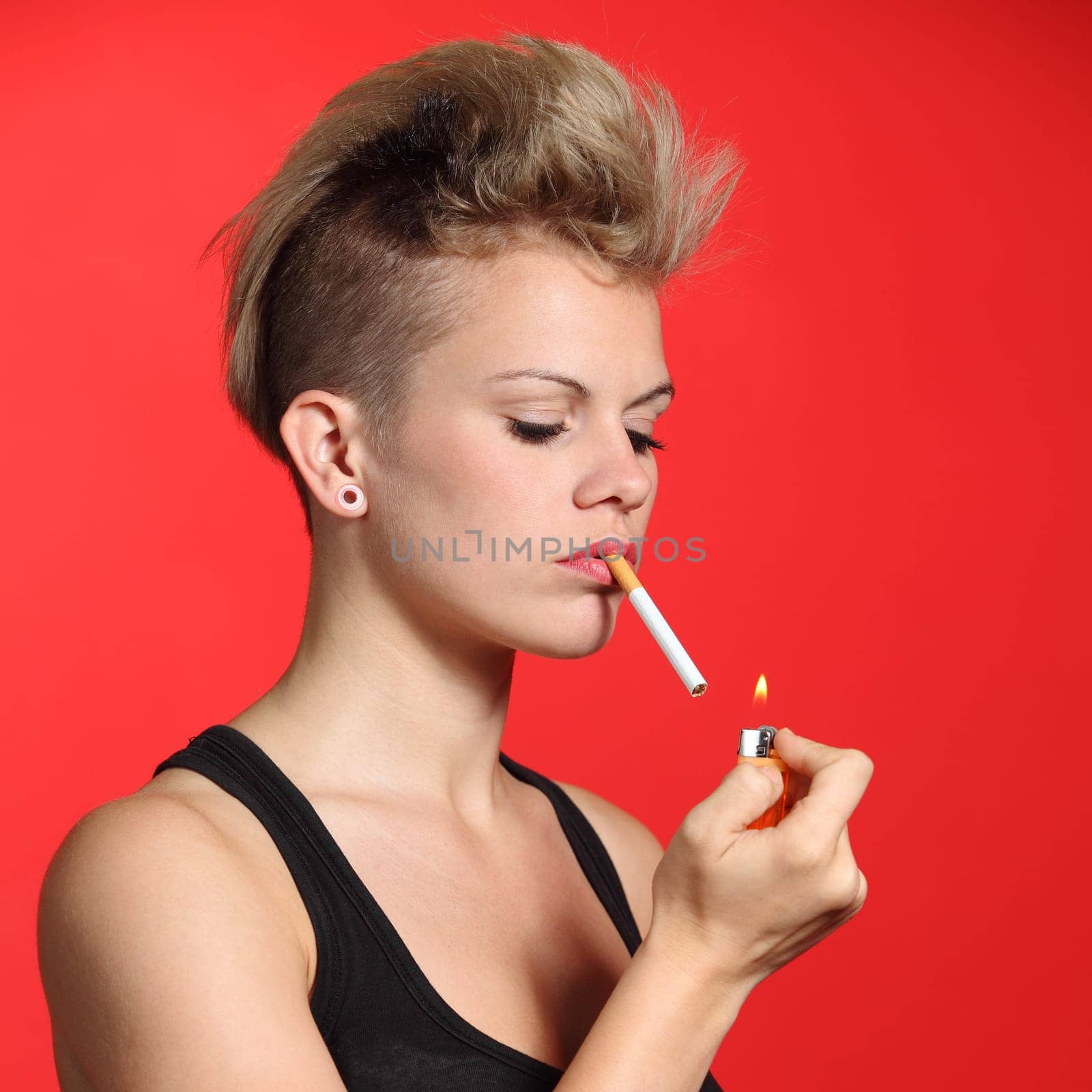 Fashion woman lighting a cigarette with a red background