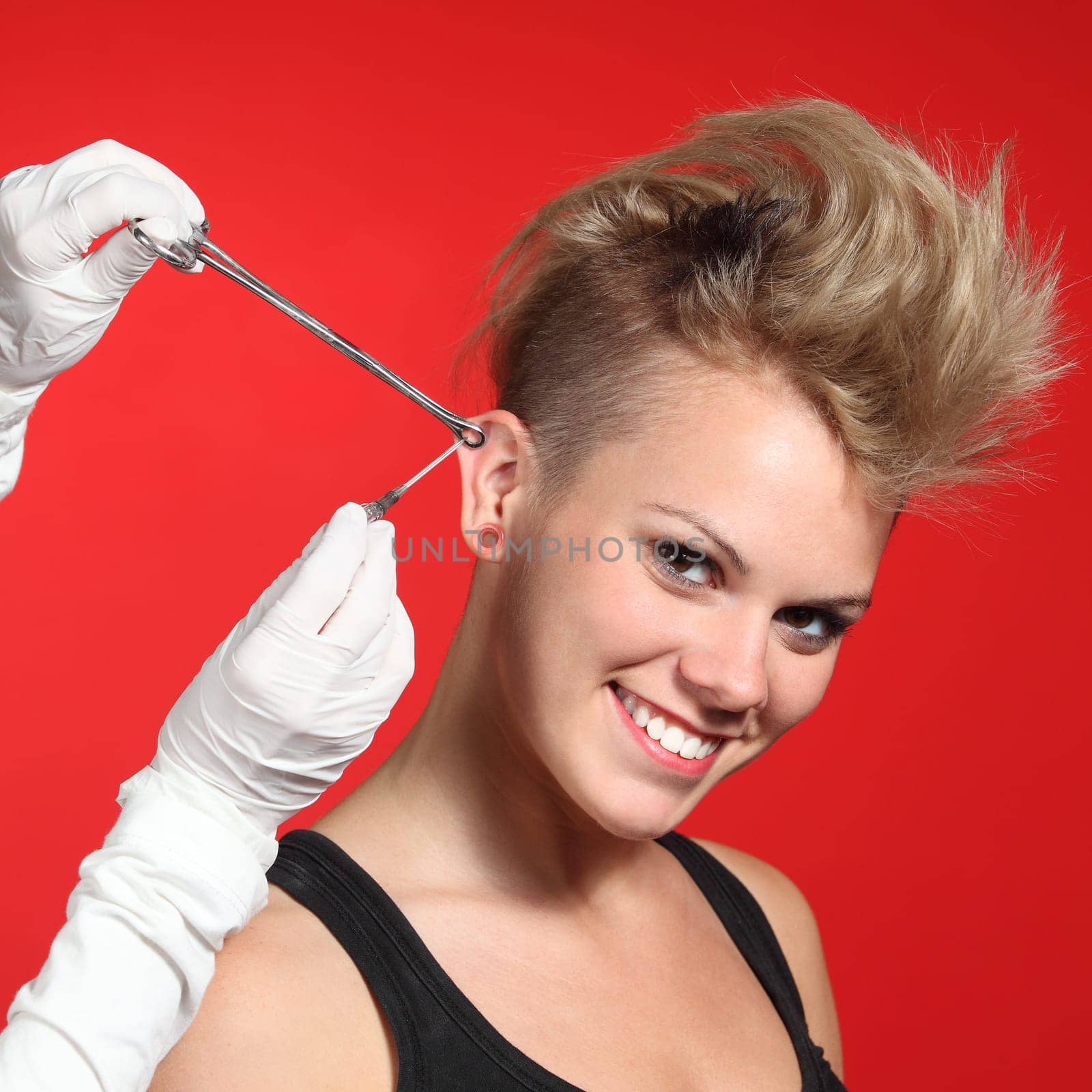 Professional hands making a piercing hole to a fashion woman on a red background