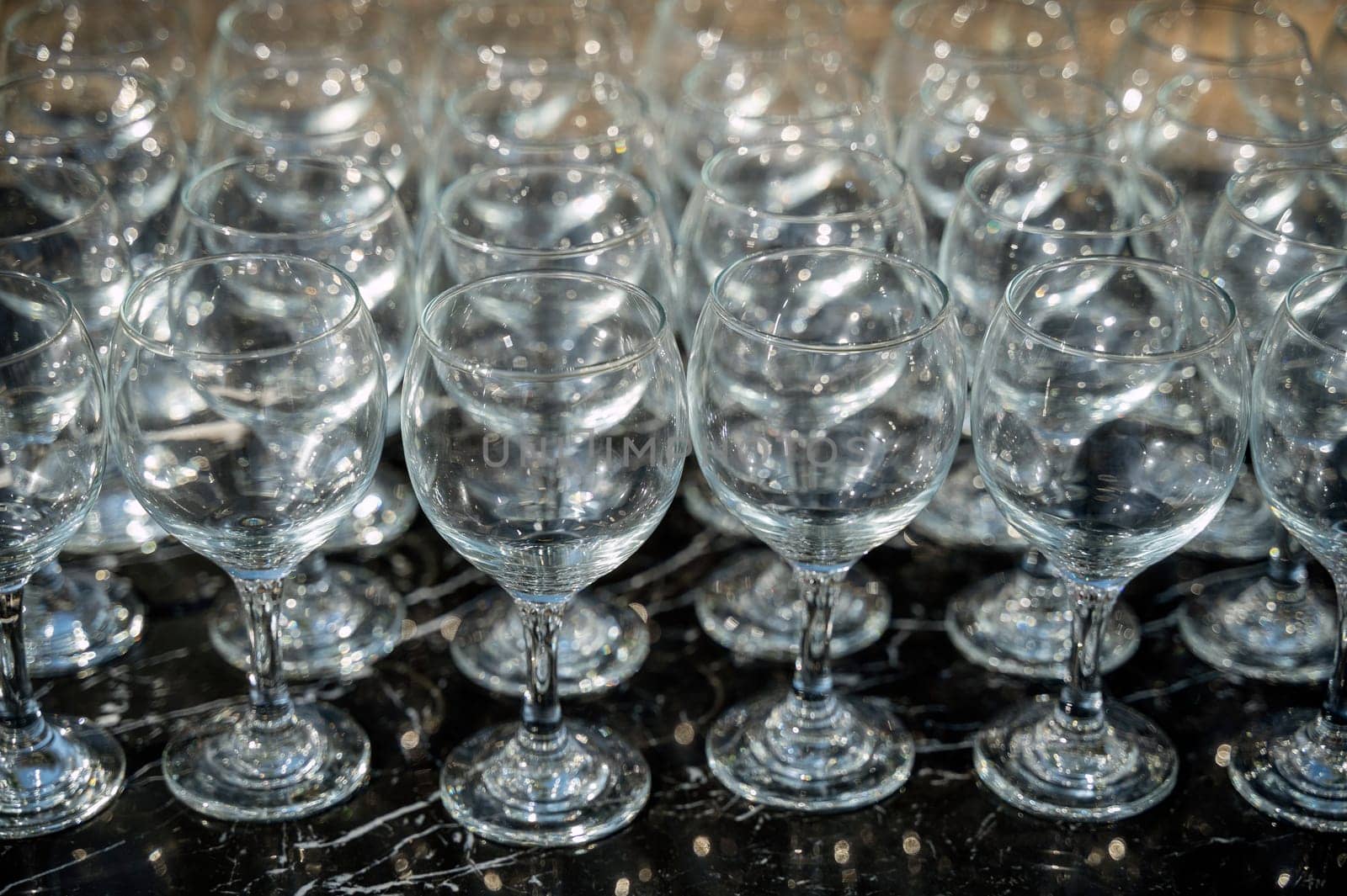 Many empty clean wine glasses on dark background in daylight. wine glasses, bar, glass, rows, empty glass, brown, transparent, glass, many. Wine glasses on black background close-up.