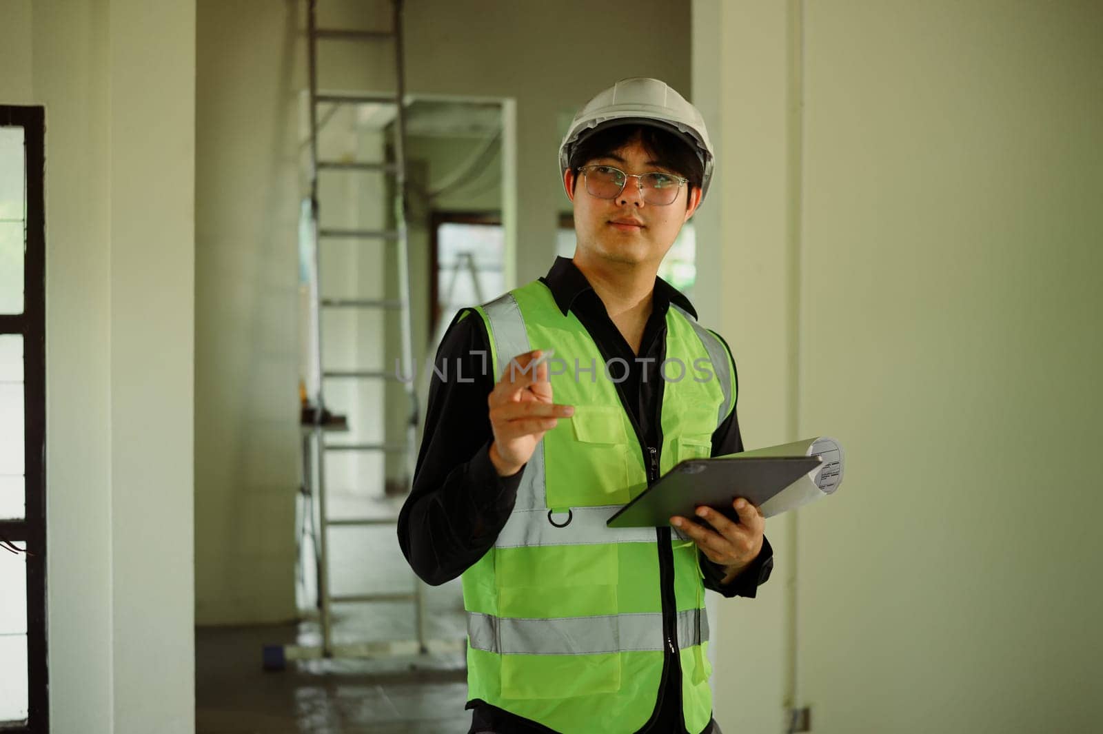 Architect or site supervisor holding tablet and overseeing progress at a renovation site.