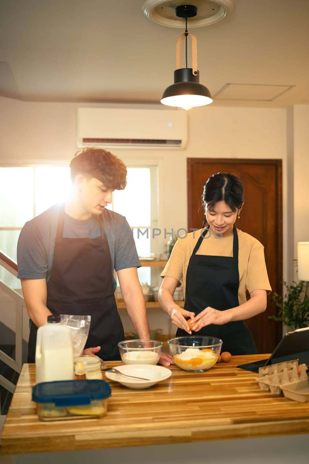Young man and woman preparing homemade pancake in a cozy kitchen.