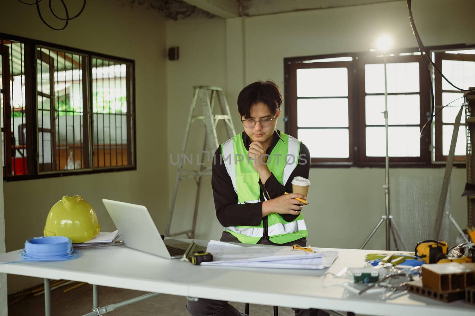 Engineer reviewing construction plans on a laptop at a job site.