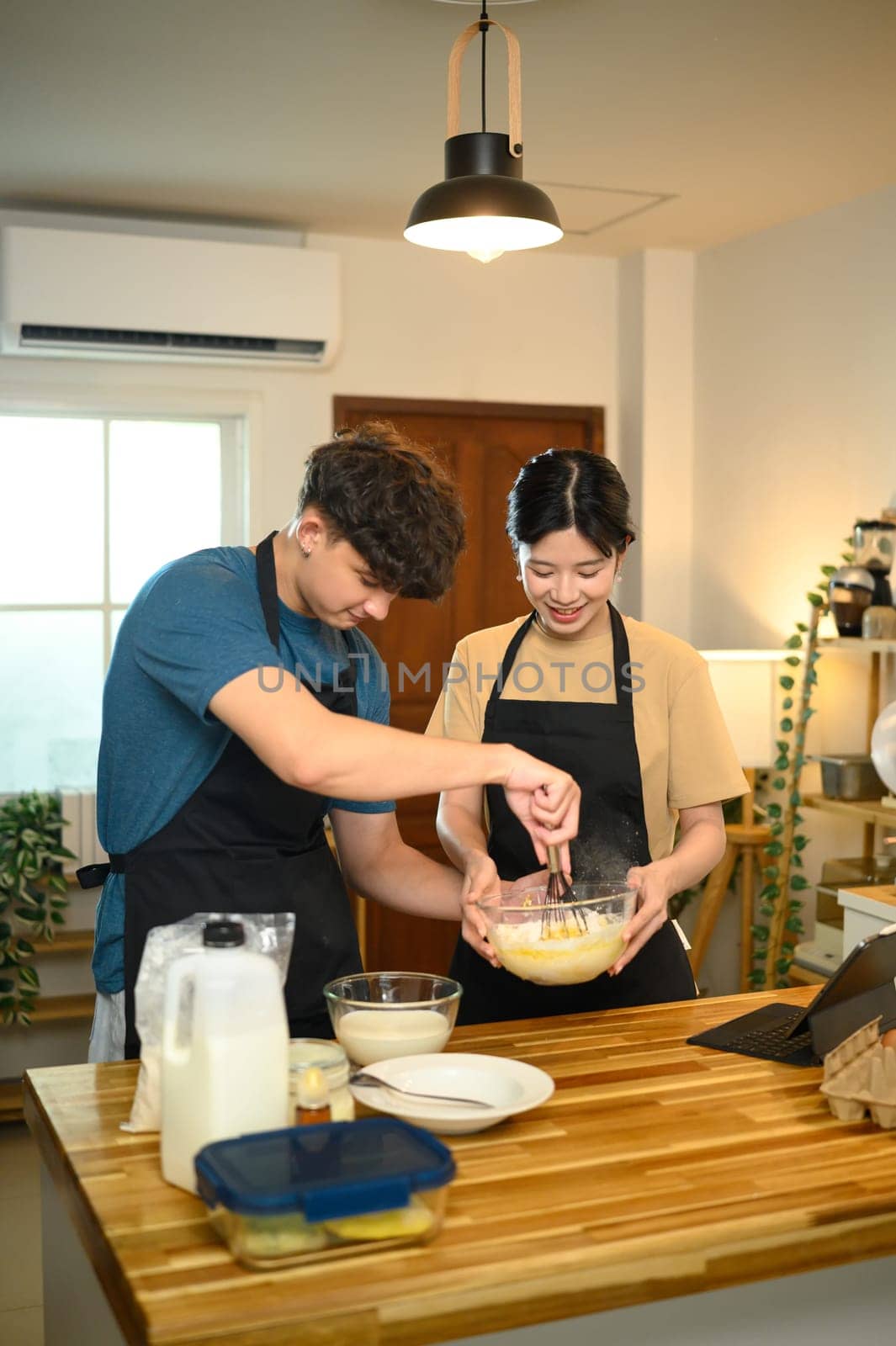Young man and woman preparing homemade pancake in a cozy kitchen.