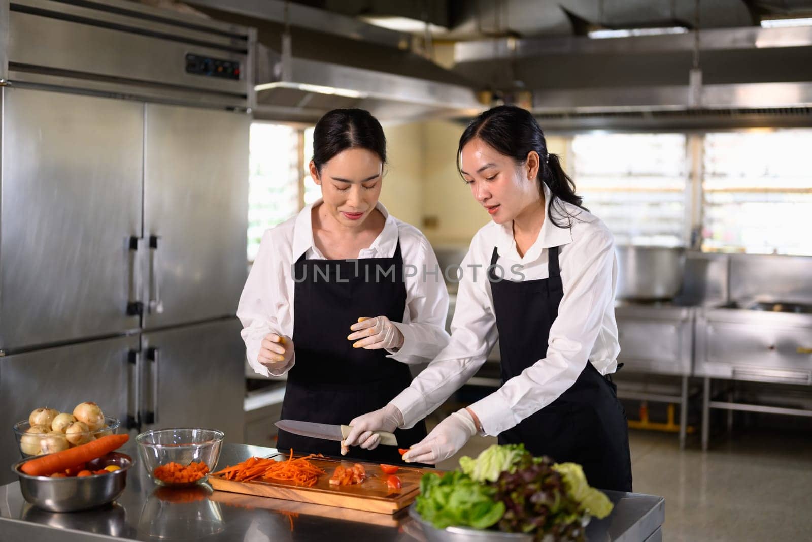 Female student learning to cut vegetables during a hands on culinary class.