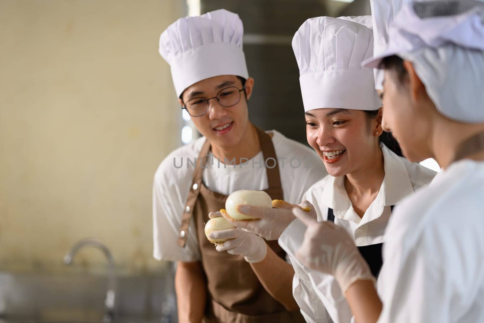 Group of trainee chefs discussing ingredients while practicing culinary skills.