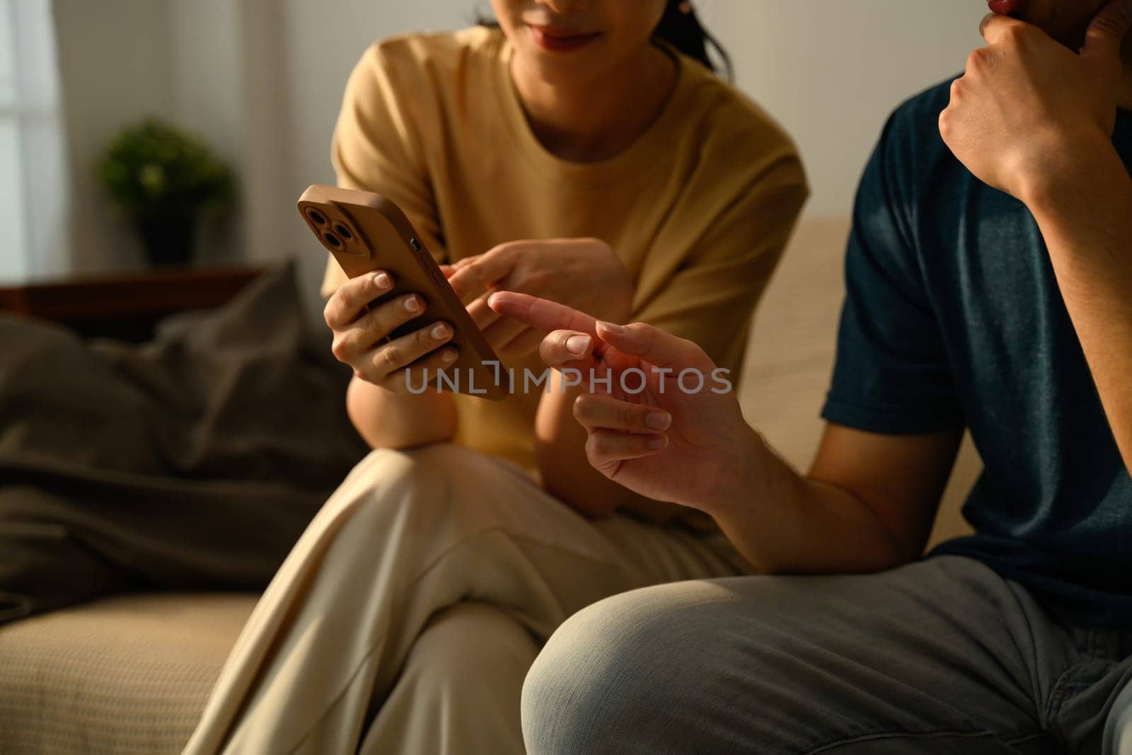 Happy young couple using smartphone together in the living room.