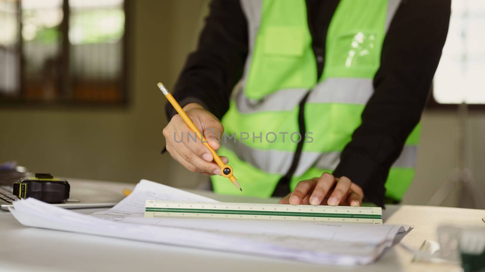 An architect is using a ruler to draw precise measurements for a construction plan.