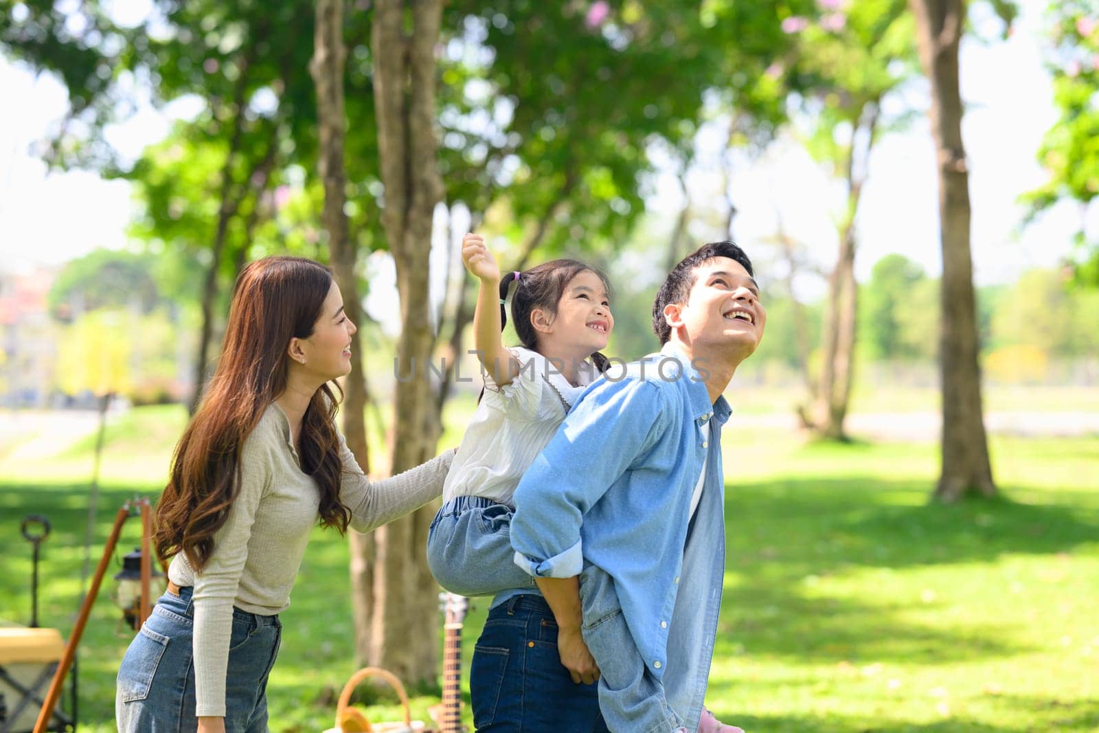 Joyful asian family playing together outdoors during camping day.