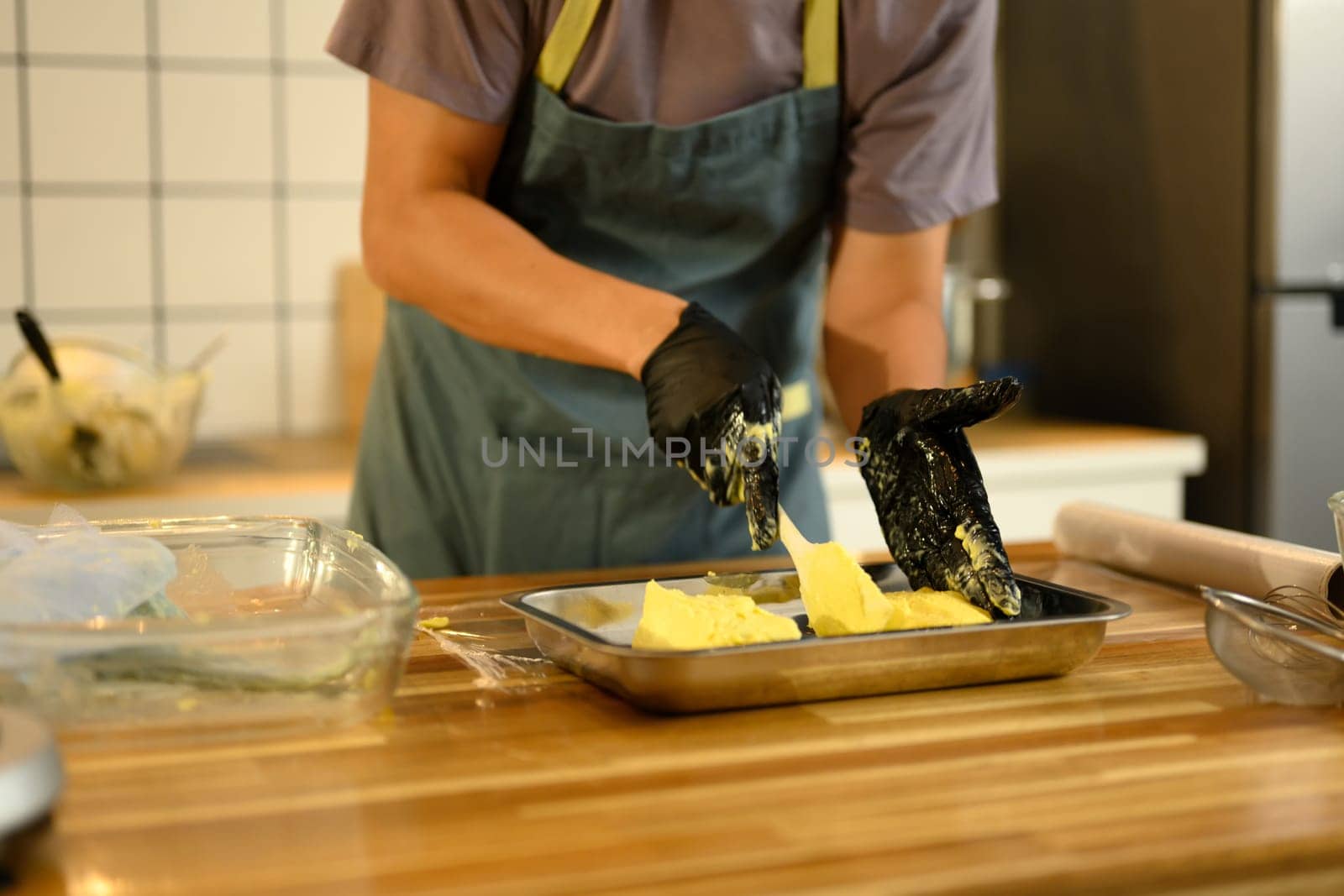 Close up of man shaping fresh homemade butter in a metal tray.