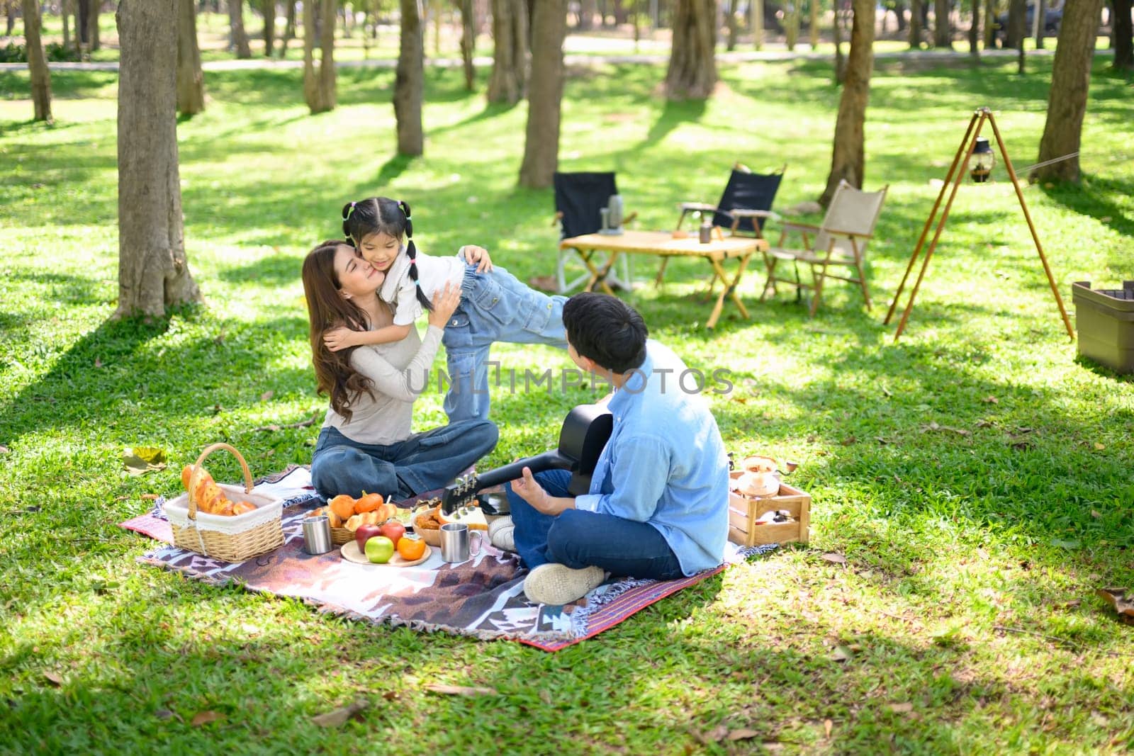 Happy parents and daughter enjoy outdoors during a camping in nature.