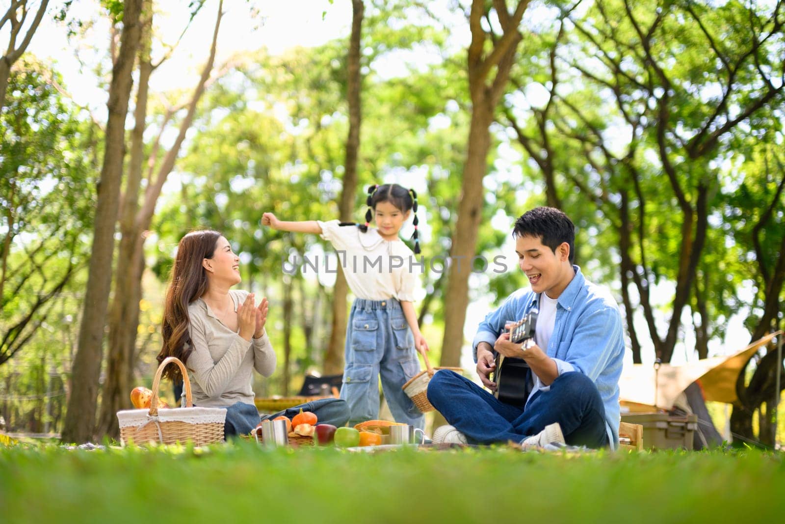 Happy family enjoying music and fun together at a campsite.