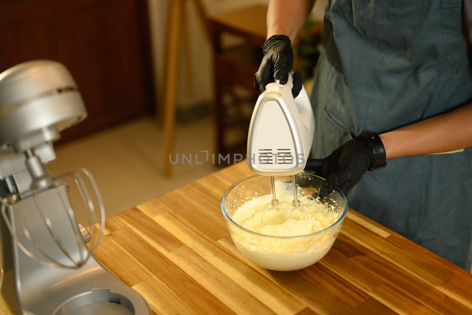 Man using electric hand mixer to whip cream in glass bowl for compound butter.