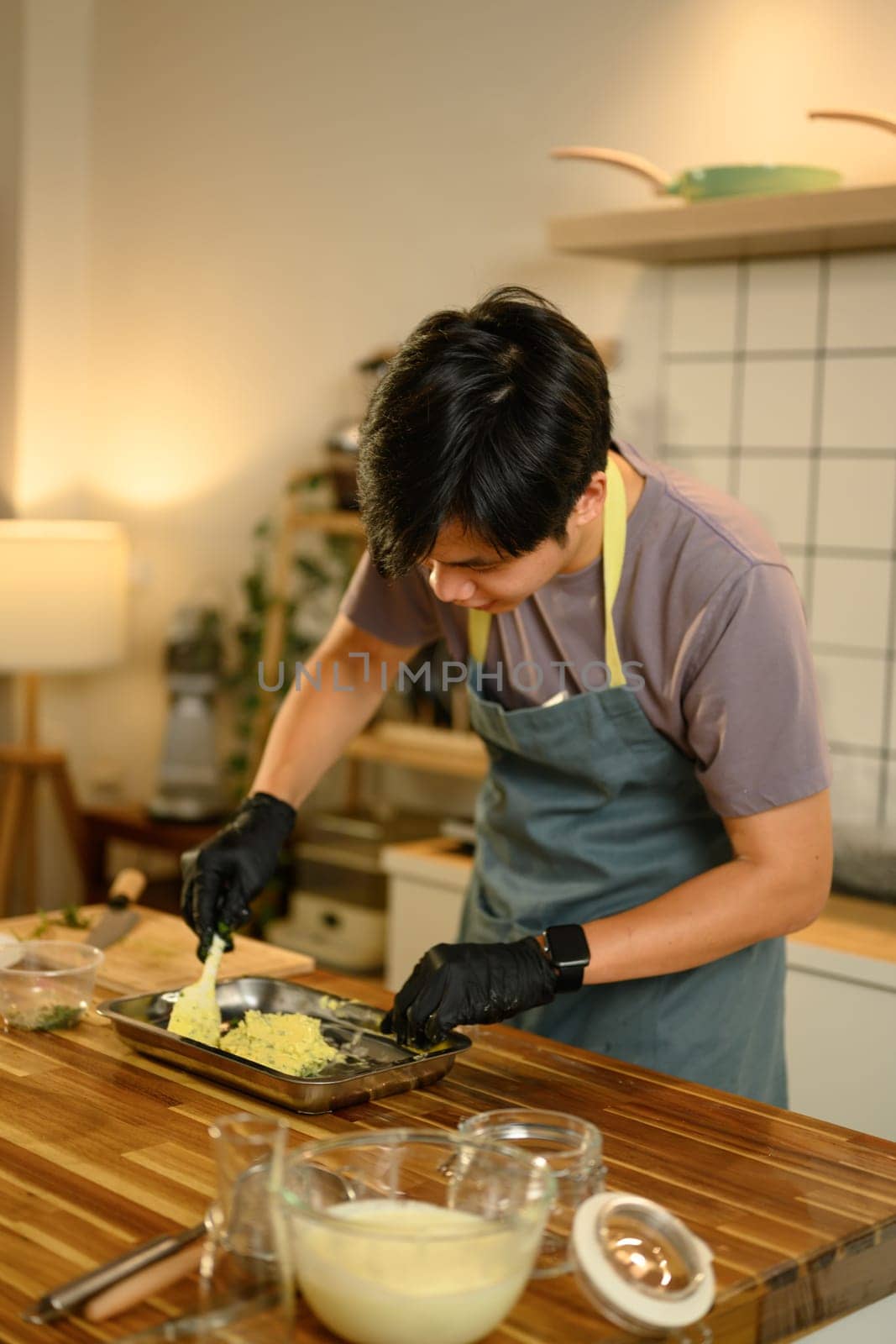 Young man making homemade compound butter on a wooden kitchen counter.