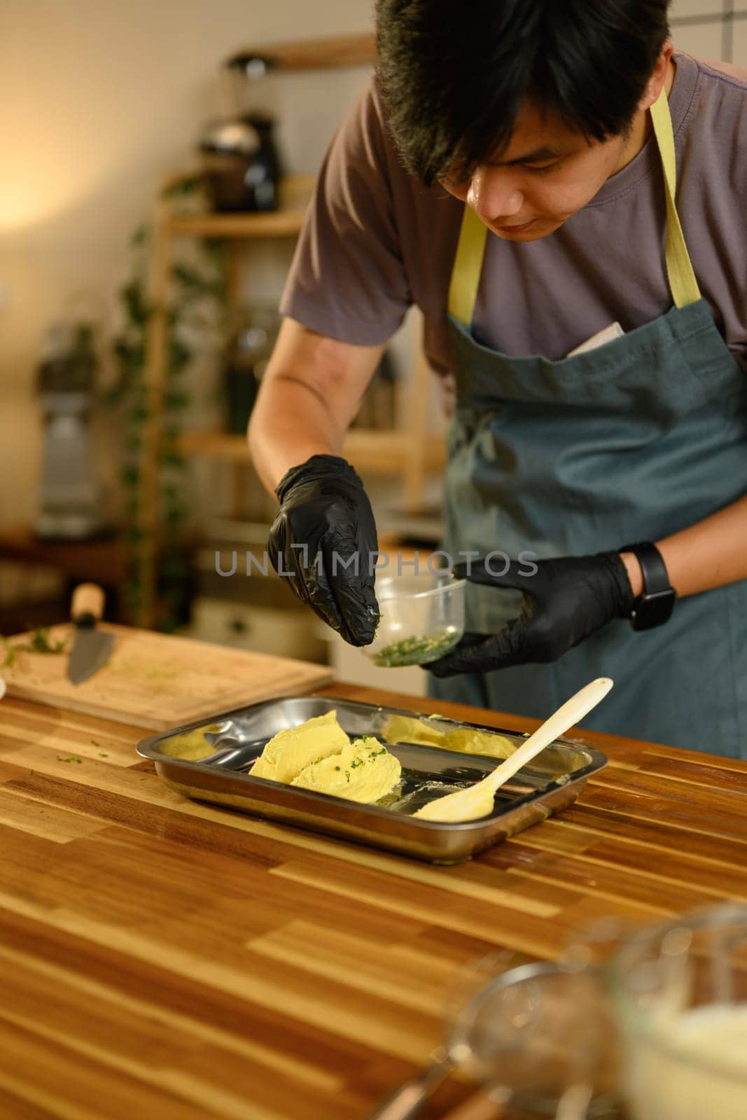 Man sprinkles fresh herbs into softened butter, preparing homemade compound butter..