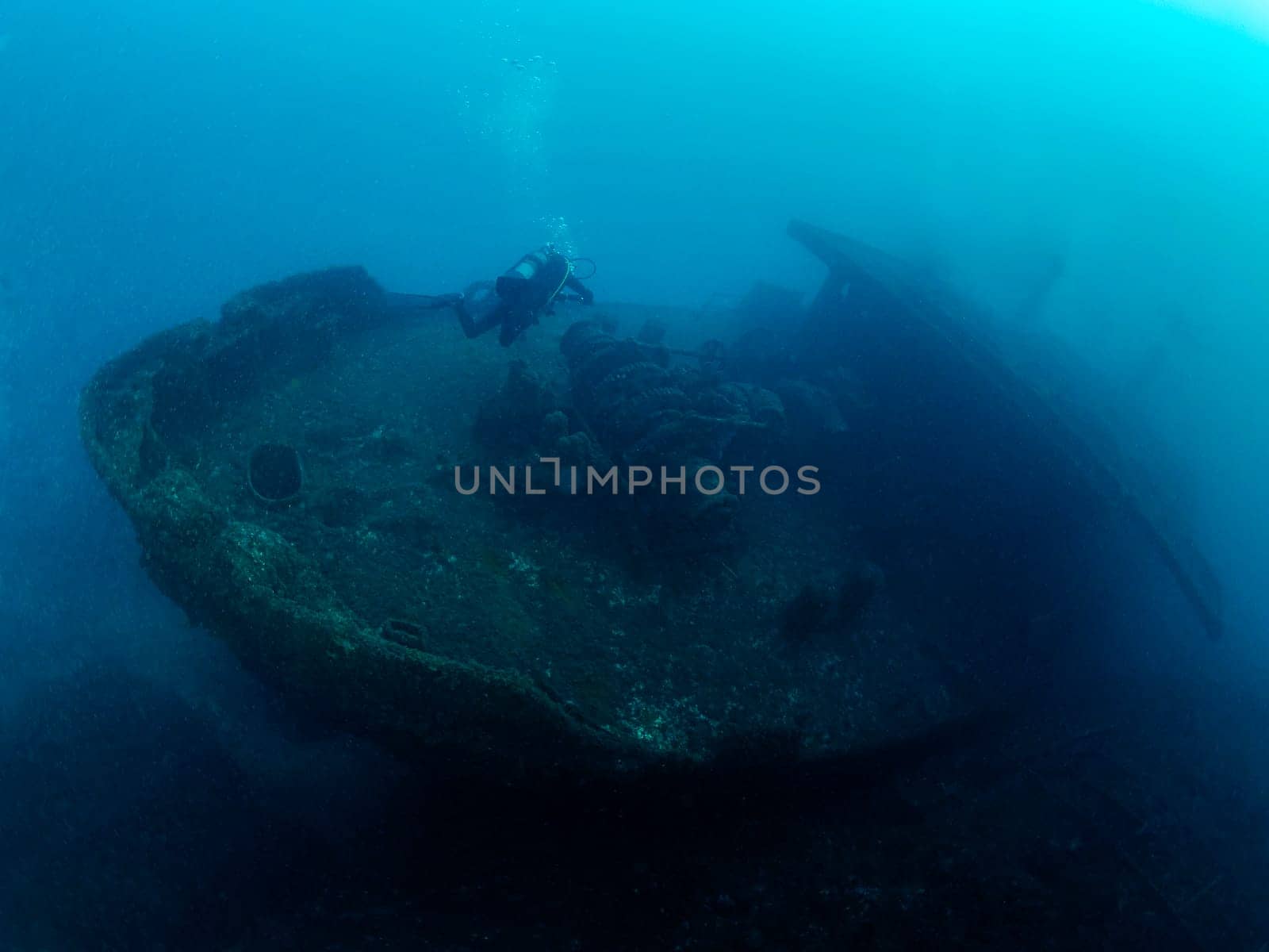 unrecognizable scuba diver diving on a sunken ship in the blue ocean, concept of underwater adventure and active leisure lifestyle, copyspace for text