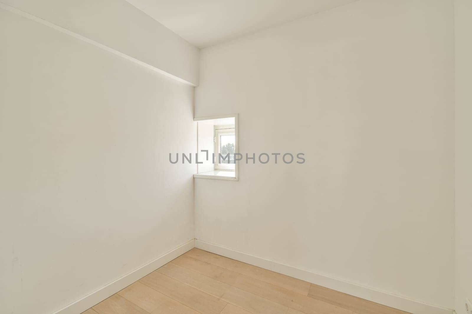 A bright and airy room featuring a small window that allows natural light to flood in, highlighting the simplicity of the space and its clean lines.