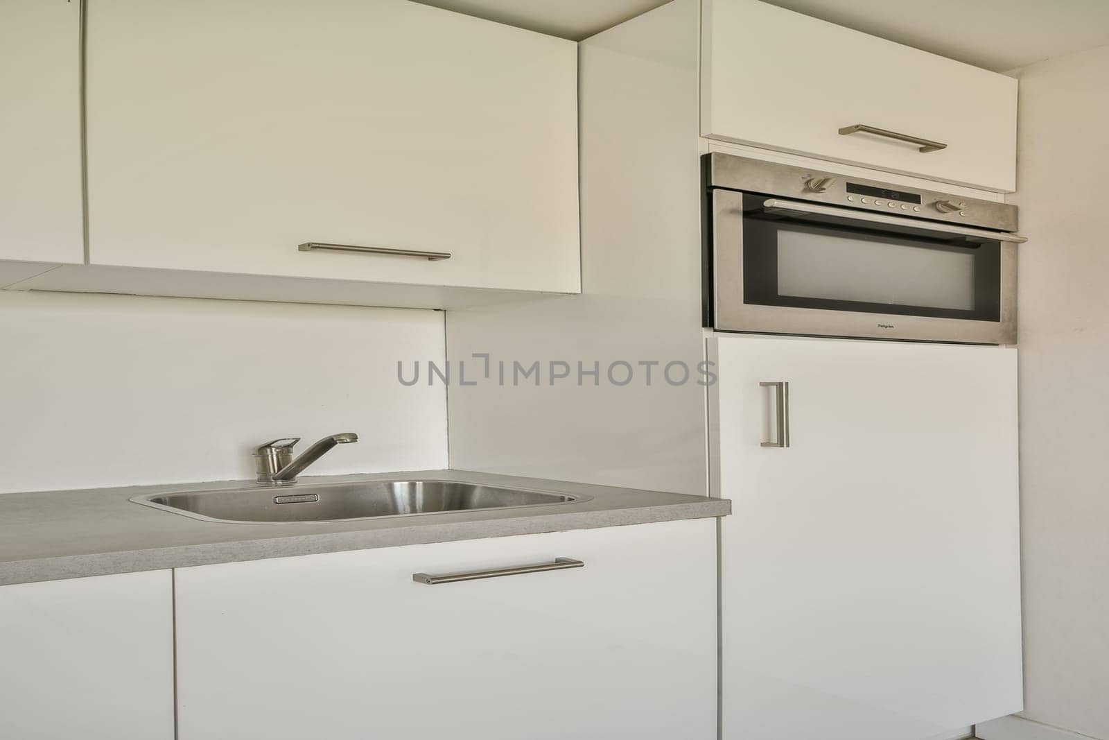 A sleek and contemporary kitchen featuring white cabinetry, stainless steel appliances, and a clean countertop. Ideal for modern living spaces.